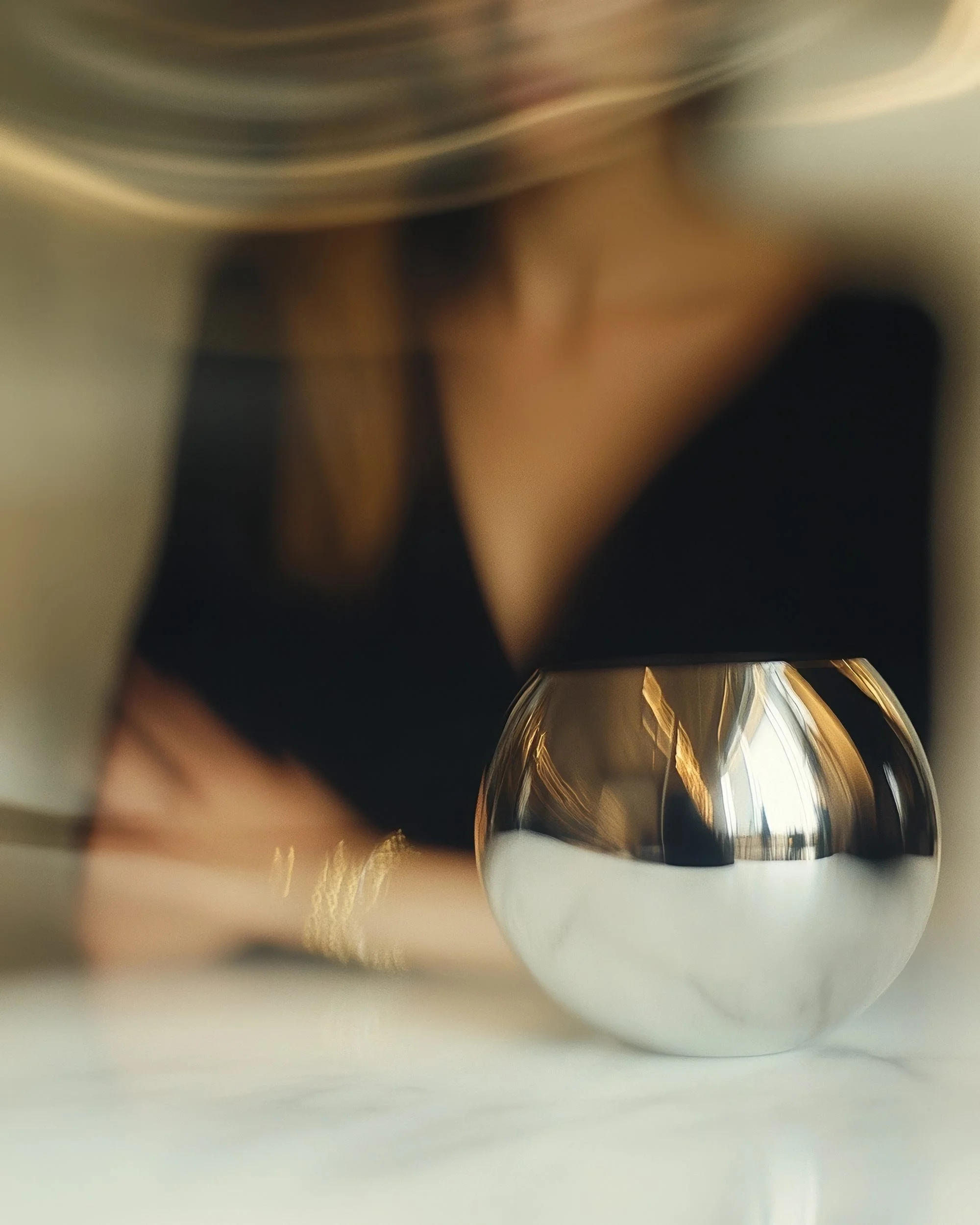 Close-up of a silver and white object with curved reflections on its surface, partially obscured.