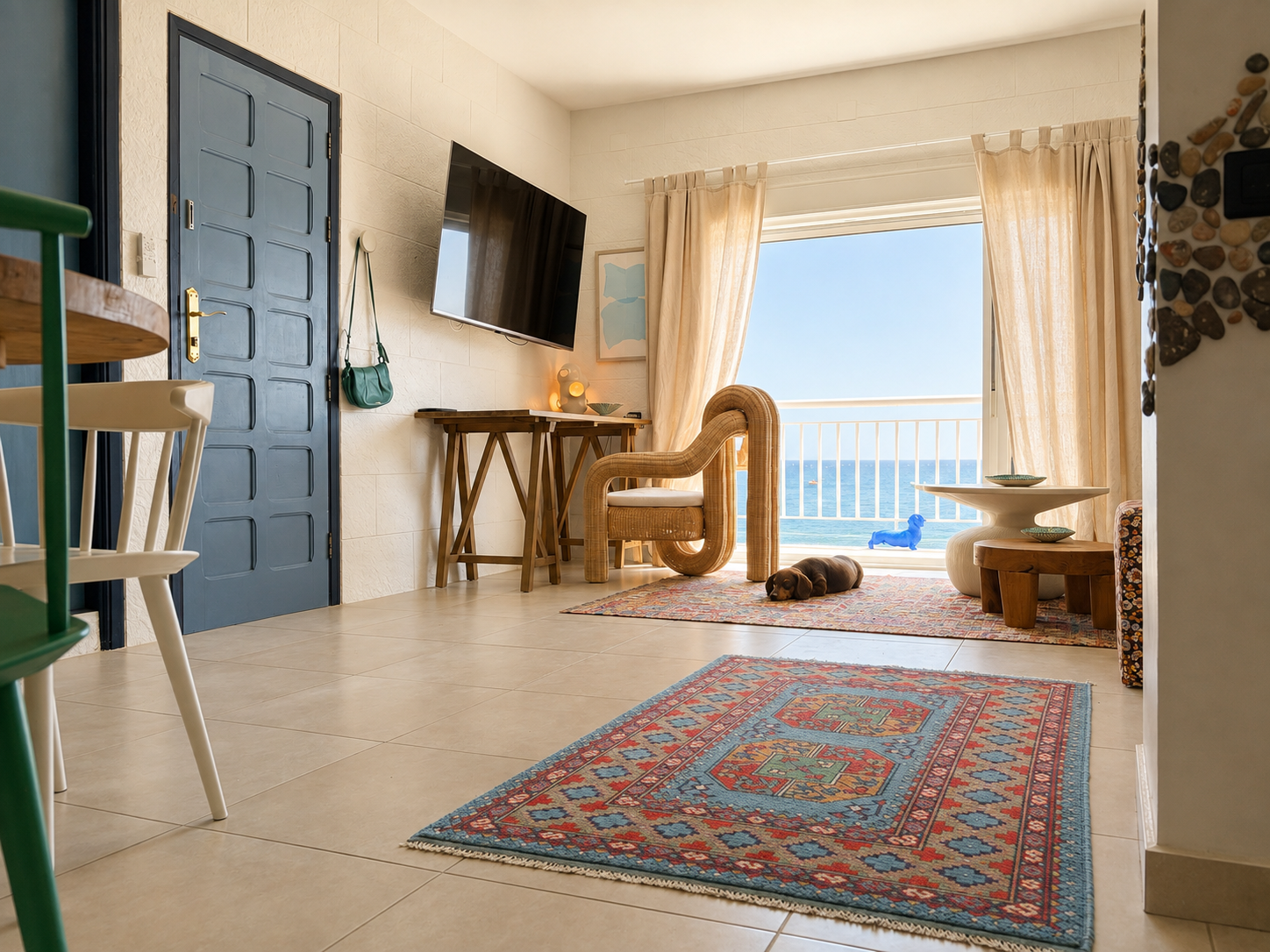 Open-concept living and kitchen area with woven rattan chairs, a colorful rug, and decorative wall art, featuring white brick walls, blue doors, and modern furniture.