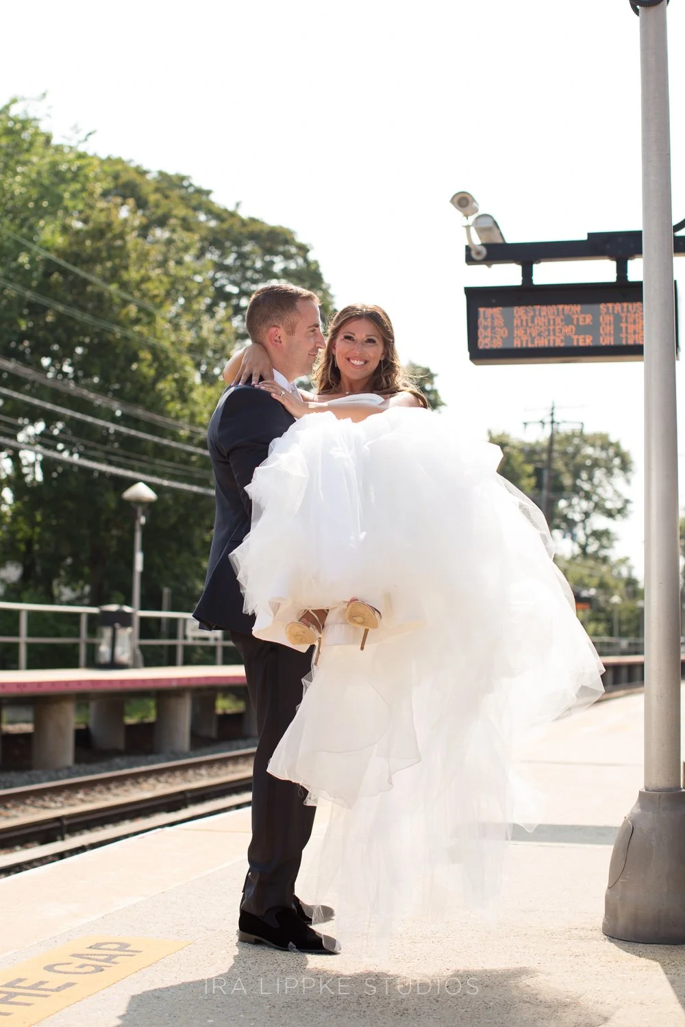 The newlyweds embrace at the train station, creating a romantic portrait that blends timeless elegance with Long Island charm.