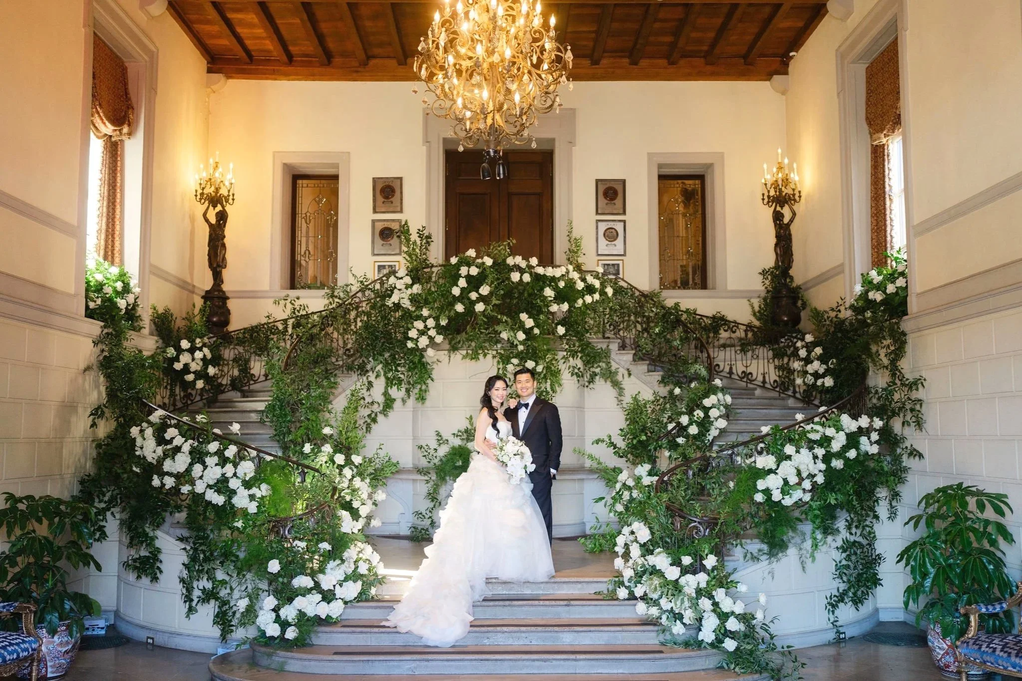 On Oheka Castle’s grand staircase, Erica and Ben were framed by lush greenery and cascading white florals, creating a moment that felt both timeless and effortlessly elegant. The setting balanced classic romance with natural softness, offering a quie