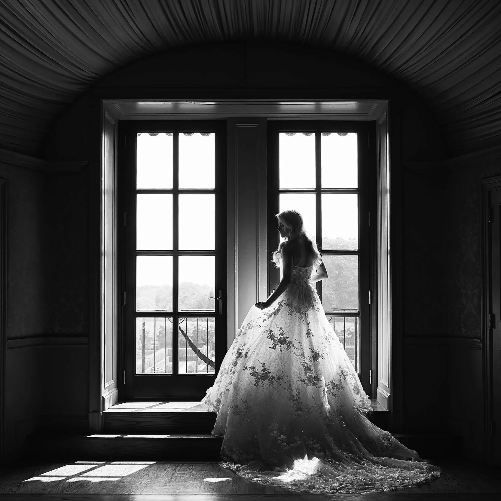 Silhouette of a bride posing in front of the balcony windows in the bridal suite of Oheka Castle 