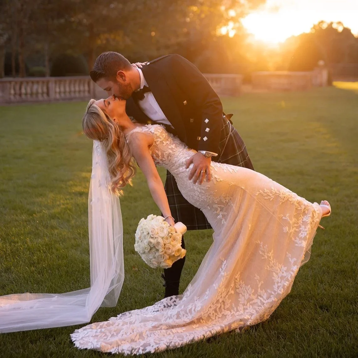 Scottish groom in his kilt dips his bride for a sunset kiss on the great lawn of Oheka Castle 