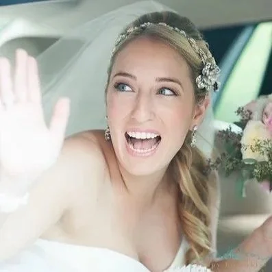 Bride waives out the window of a vintage rolls royce on her way to church for her wedding ceremony 