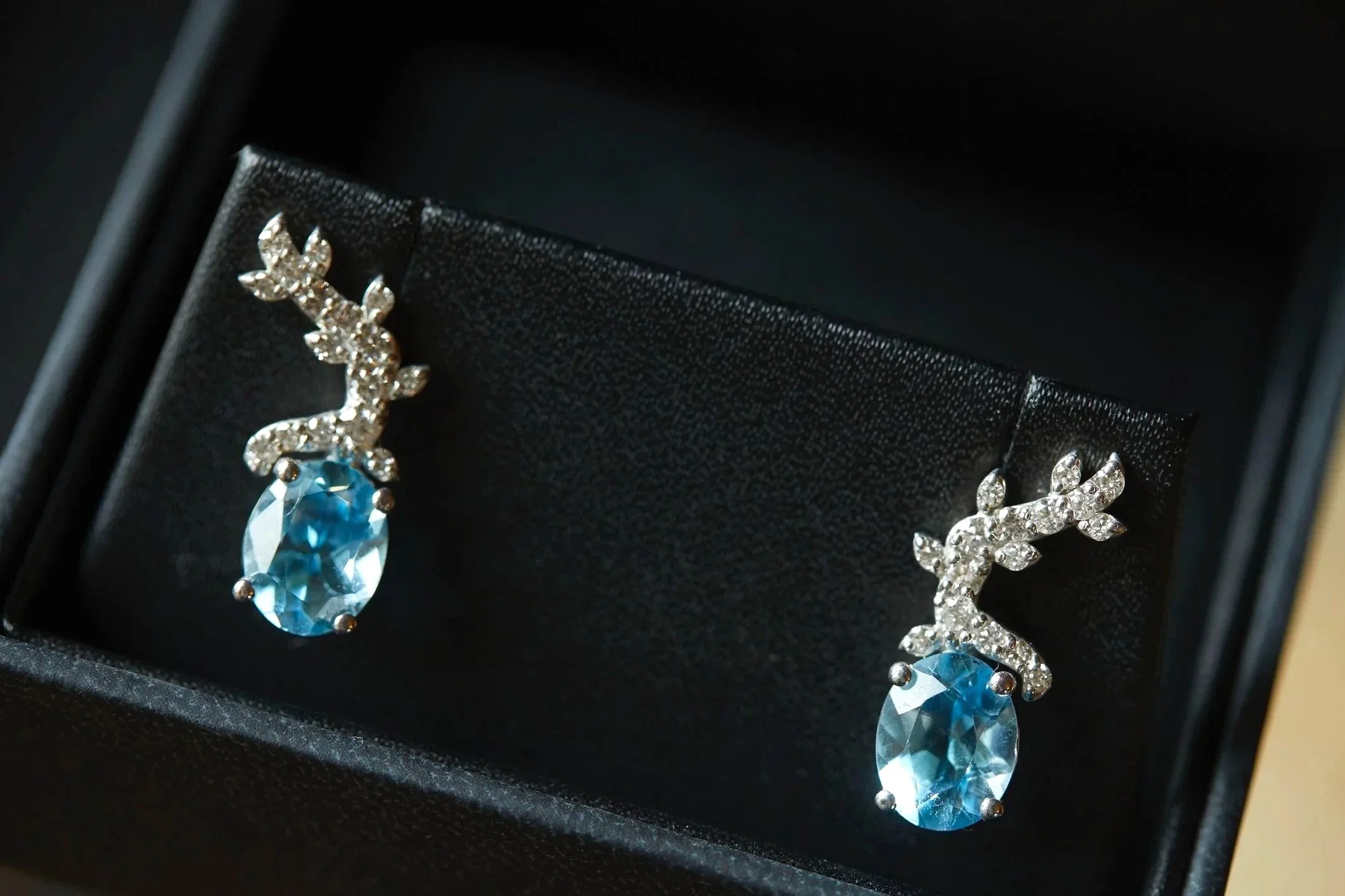 Samantha’s blue gemstone wedding earrings styled in an elegant black jewelry box during bridal preparations.