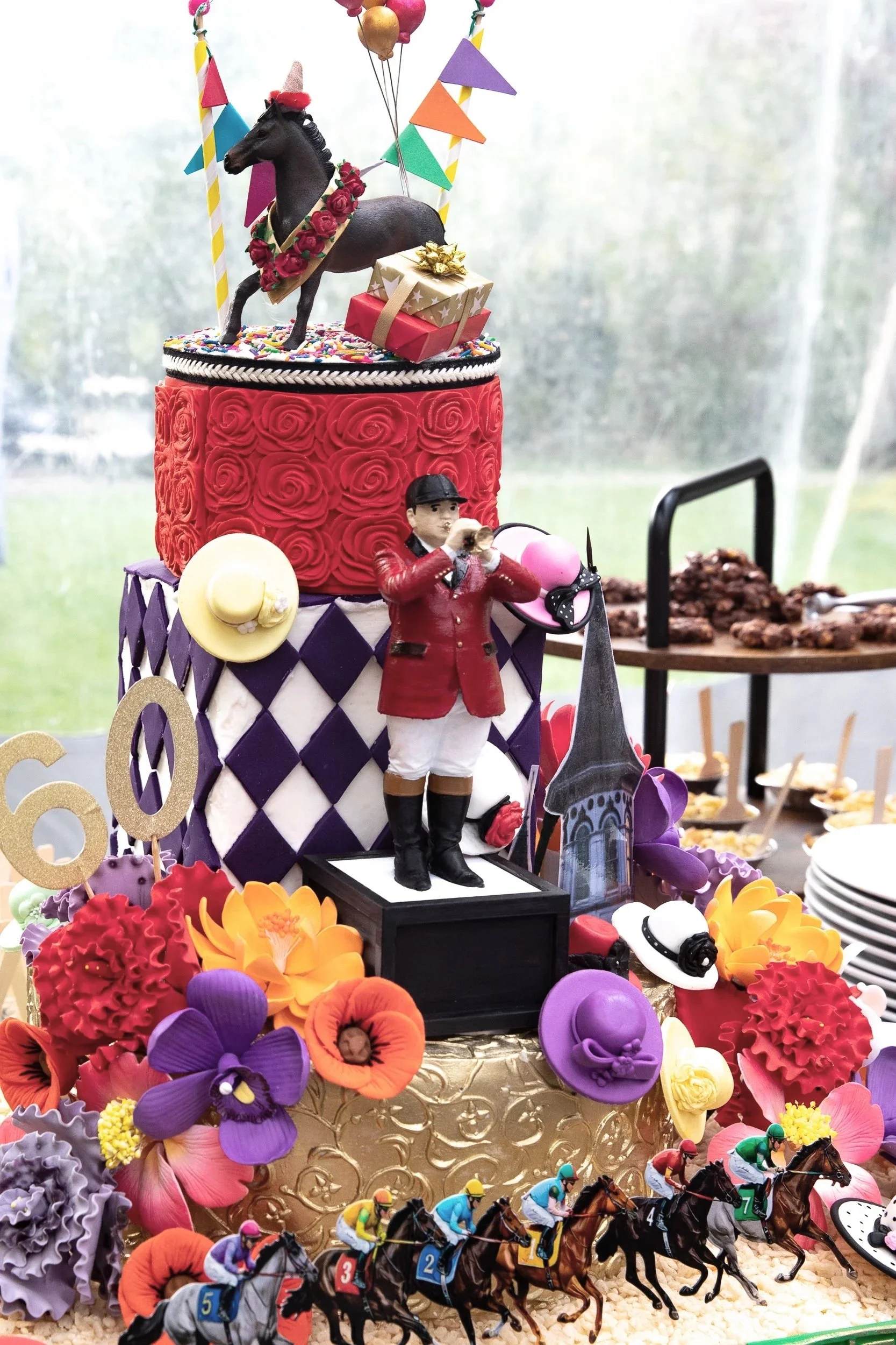 A whimsical Derby-inspired confection display layered with florals, racing silks, and vibrant equestrian details.
