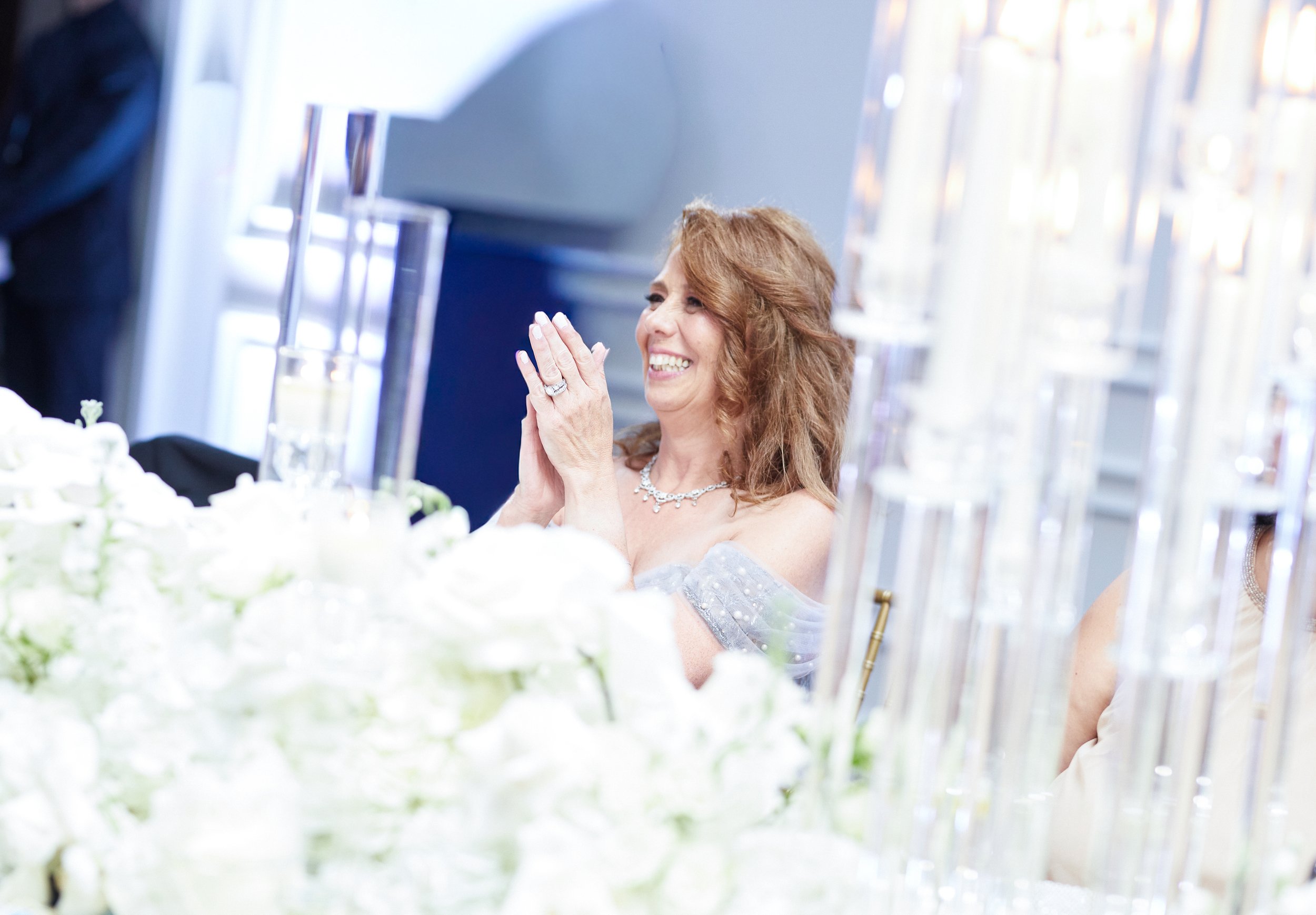 Samantha’s mother reacting emotionally during the wedding reception surrounded by candlelight and white floral arrangements.