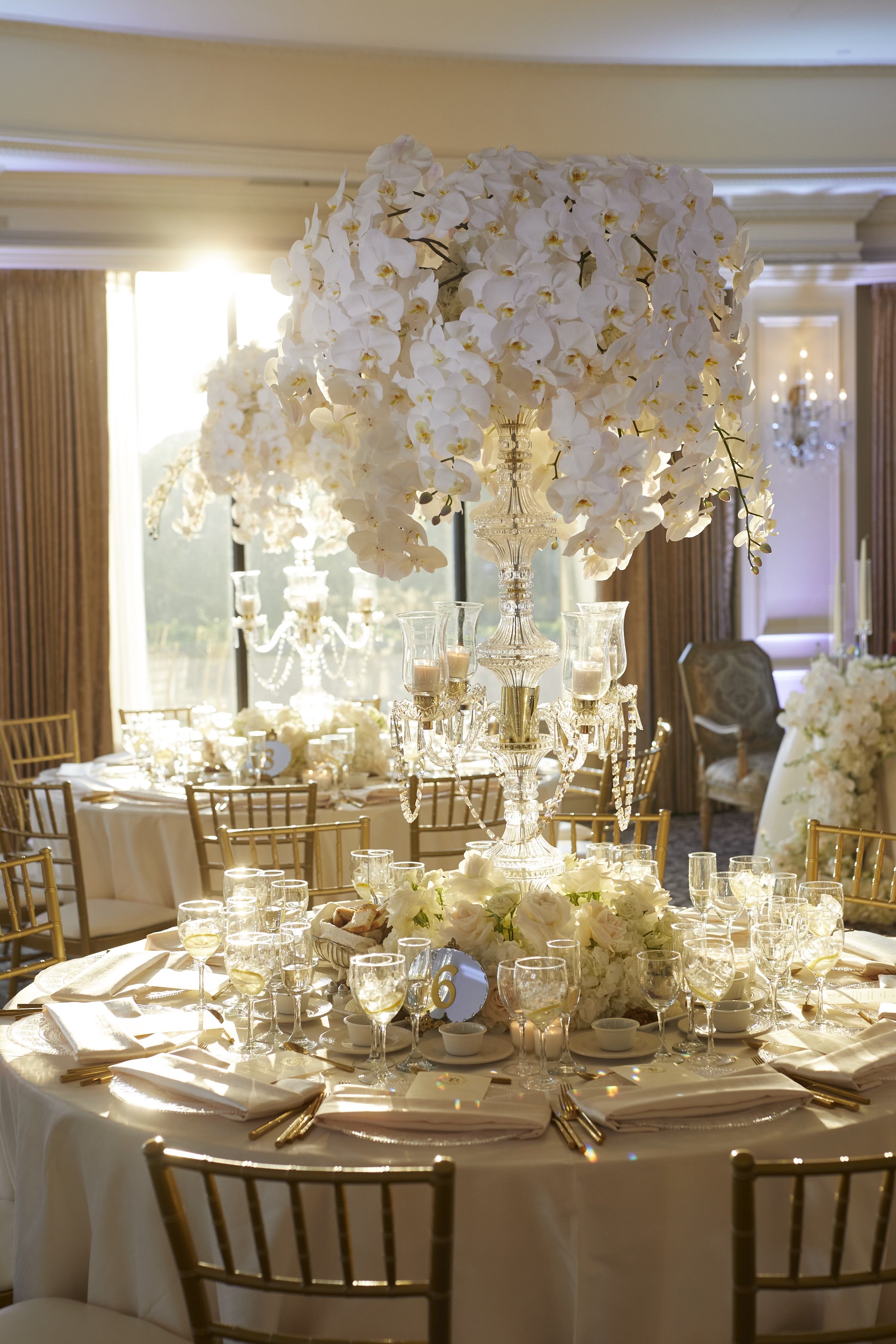 Wedding reception table with cut crystal candelabra centerpiece with cascading white phalaenopsis orchids at Oheka Castle. 