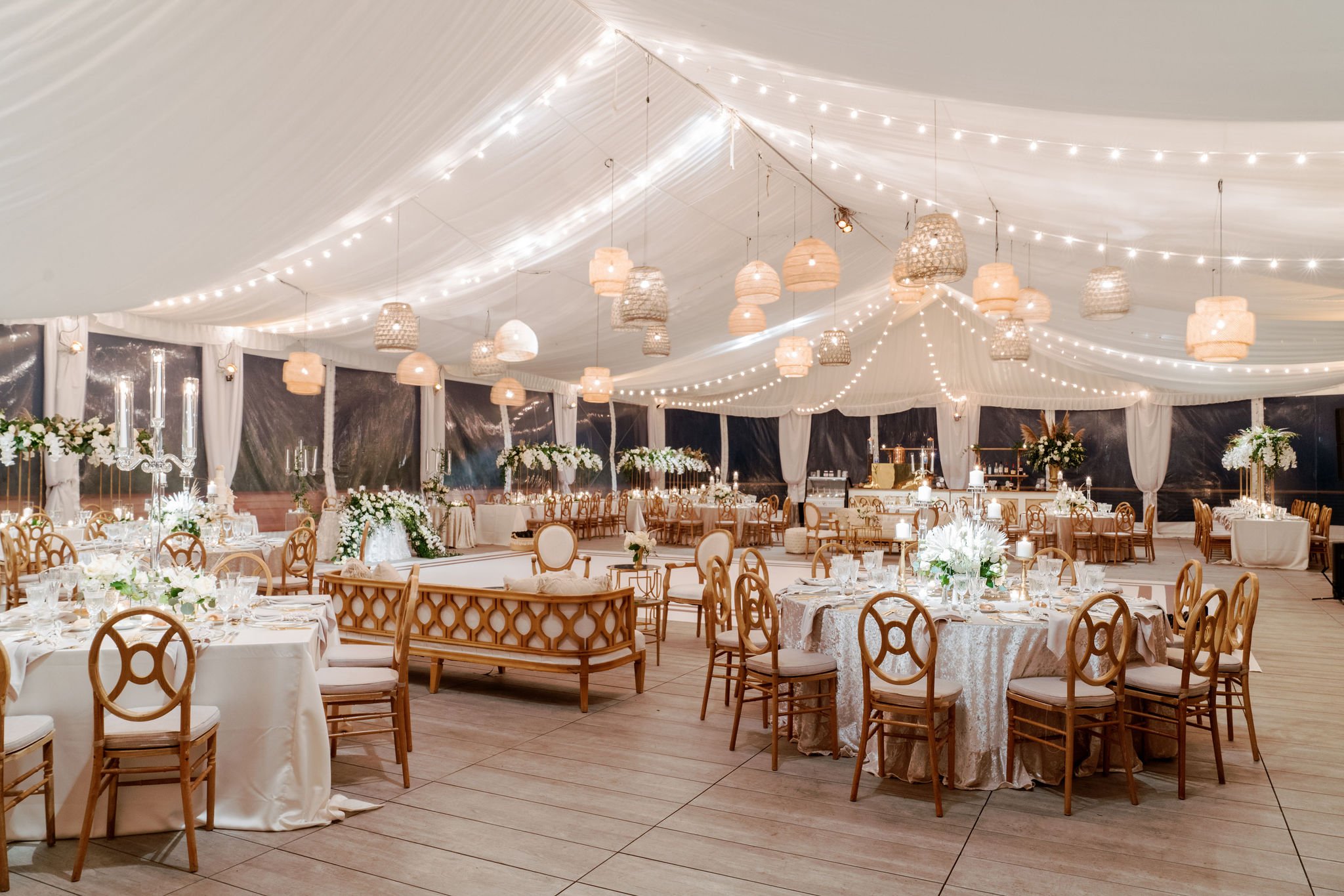 Before guests arrived, the reception tent revealed itself in a soft glow—layered with draped fabric, warm lighting, and natural textures, creating an atmosphere that felt both elevated and effortlessly coastal.