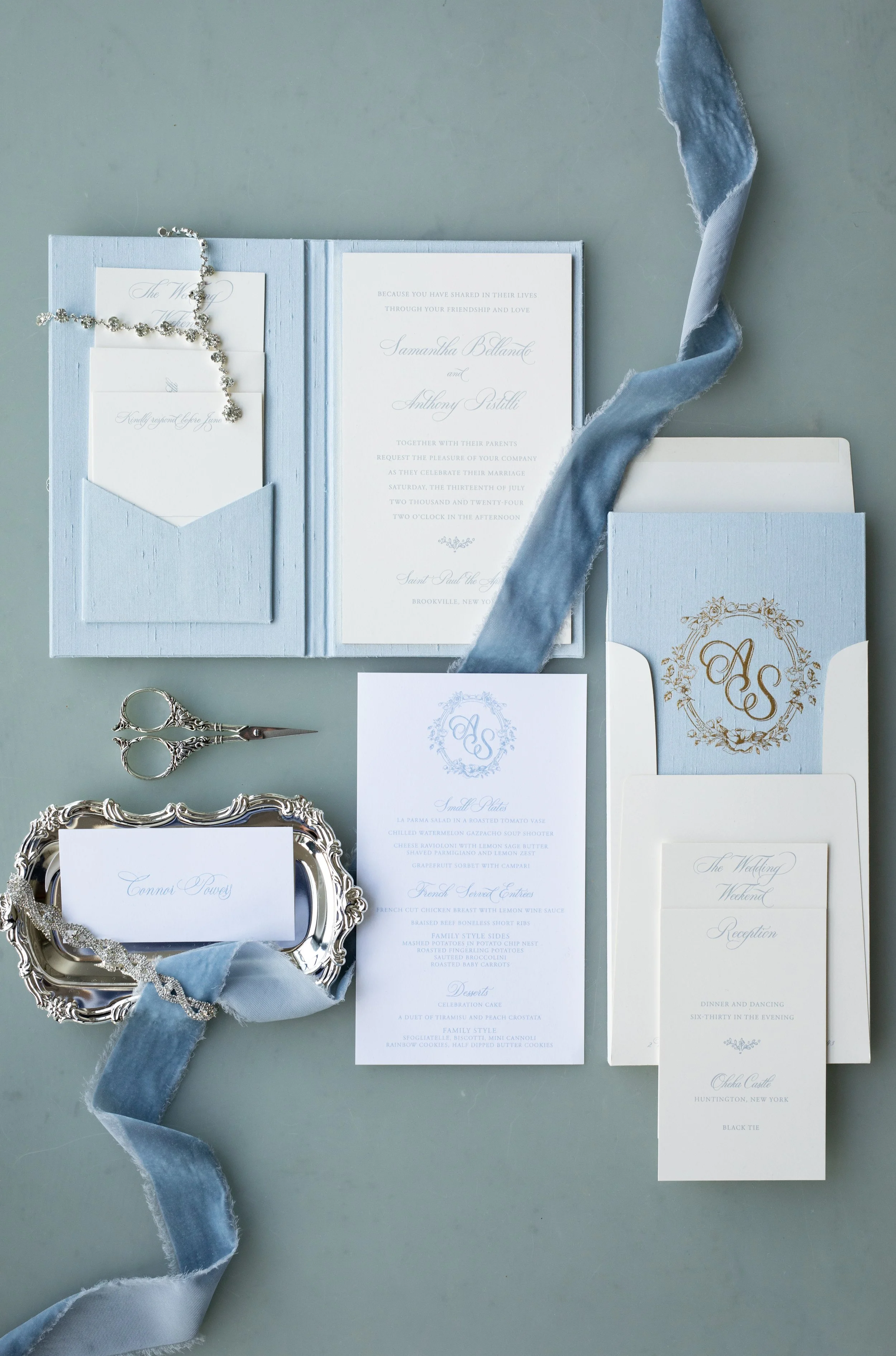 Samantha and Anthony’s custom wedding invitation suite featuring soft blue tones, monogrammed details, silk ribbon, and refined paper goods designed for the wedding weekend at Oheka Castle.