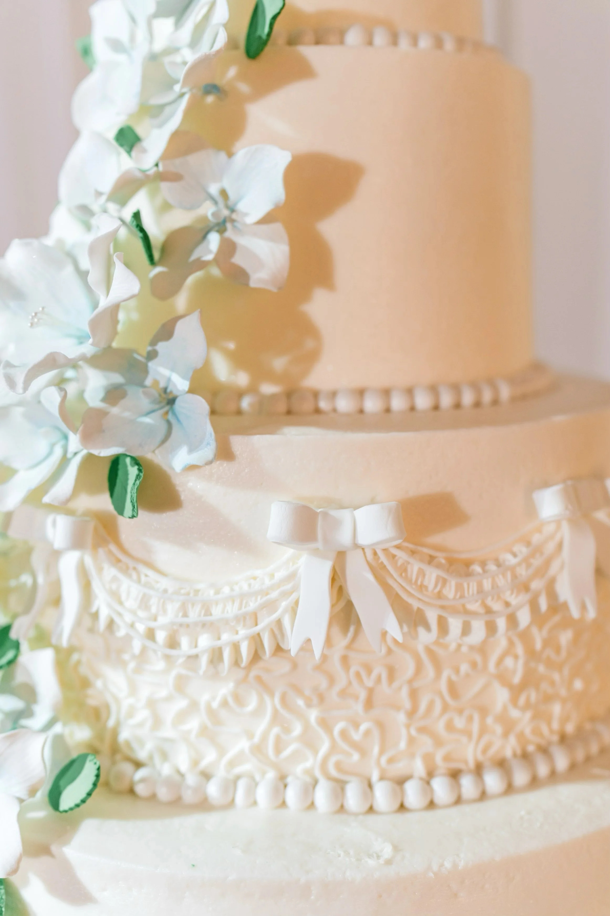 Elegant white wedding cake with intricate piping and soft blue sugar flowers