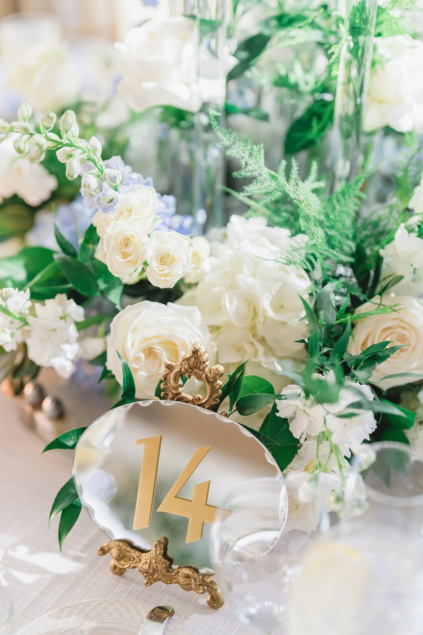 Table number 14 gold mirror detail surrounded by white roses and greenery centerpiece