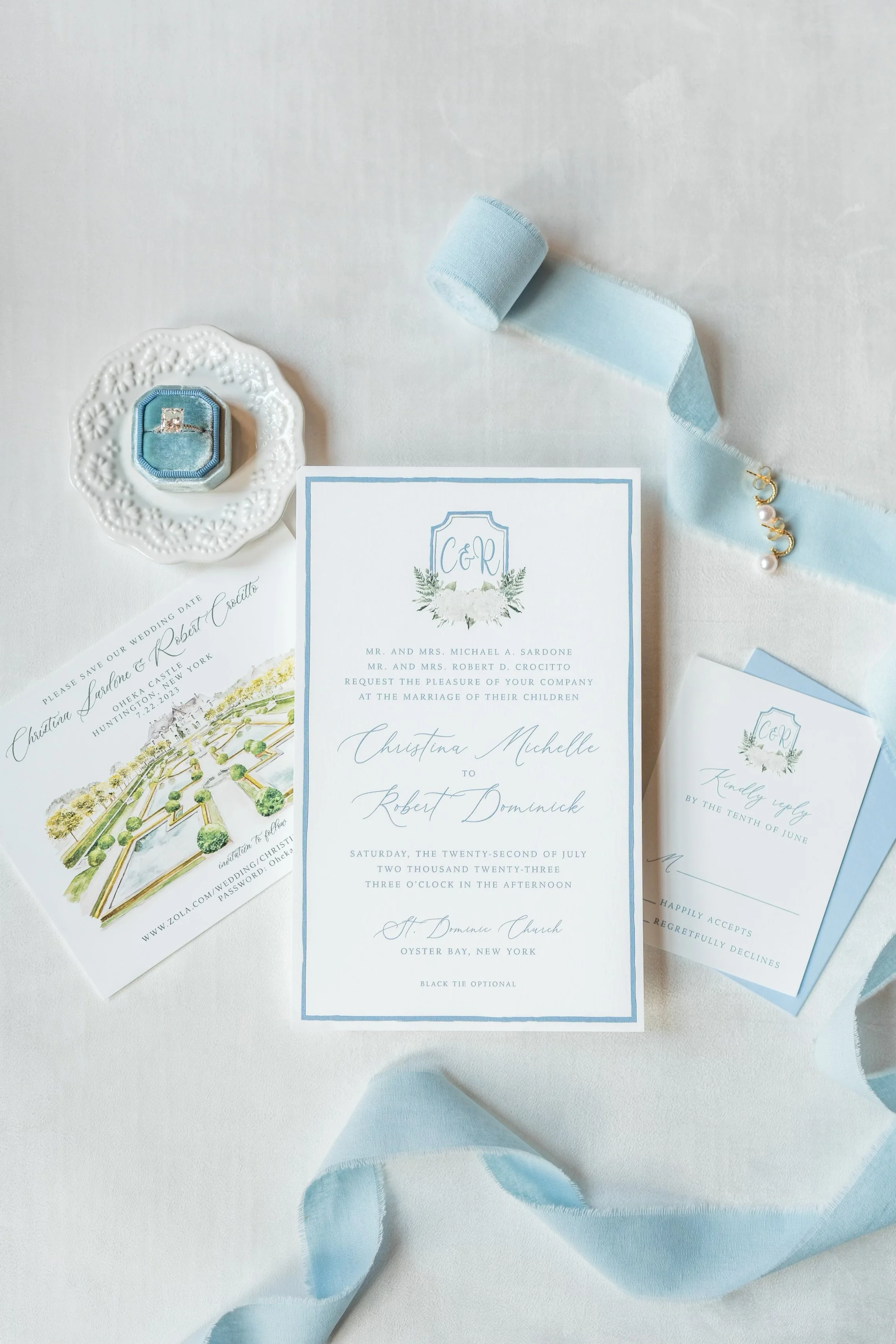 Blue and white wedding invitation suite with ribbon, ring box, and illustrated Oheka Castle details