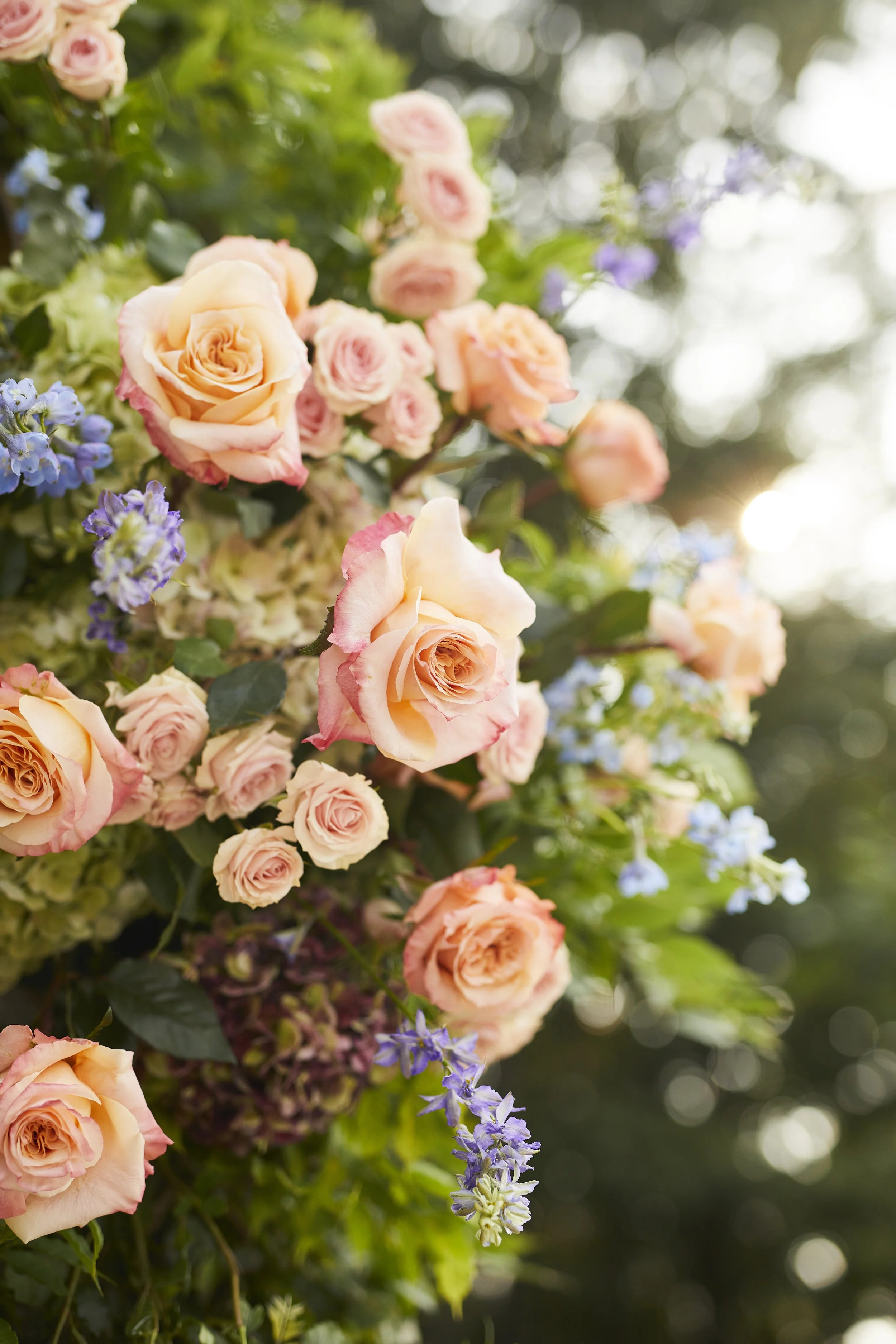 Close-up of romantic peach and blush wedding florals with soft sunlight