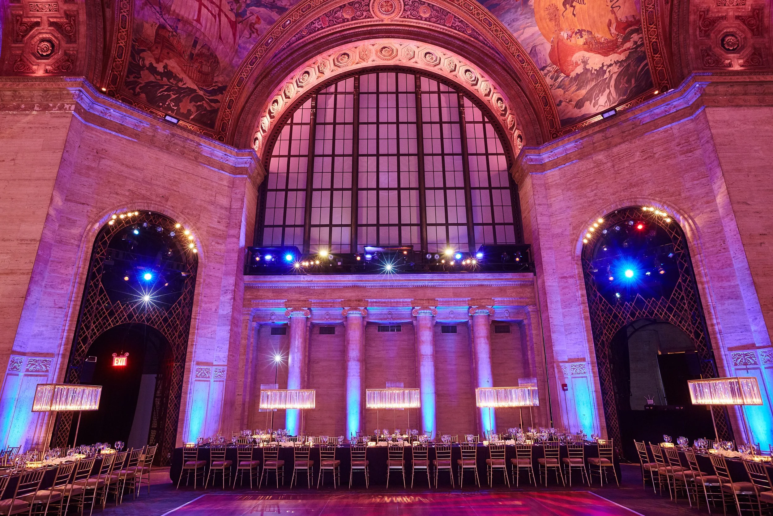 Bar Mitzvah reception design at Cipriani Wall Street in New York City — long banquet tables and glowing lighting installations set beneath the venue’s iconic arched windows, creating a balanced and elevated dining experience.