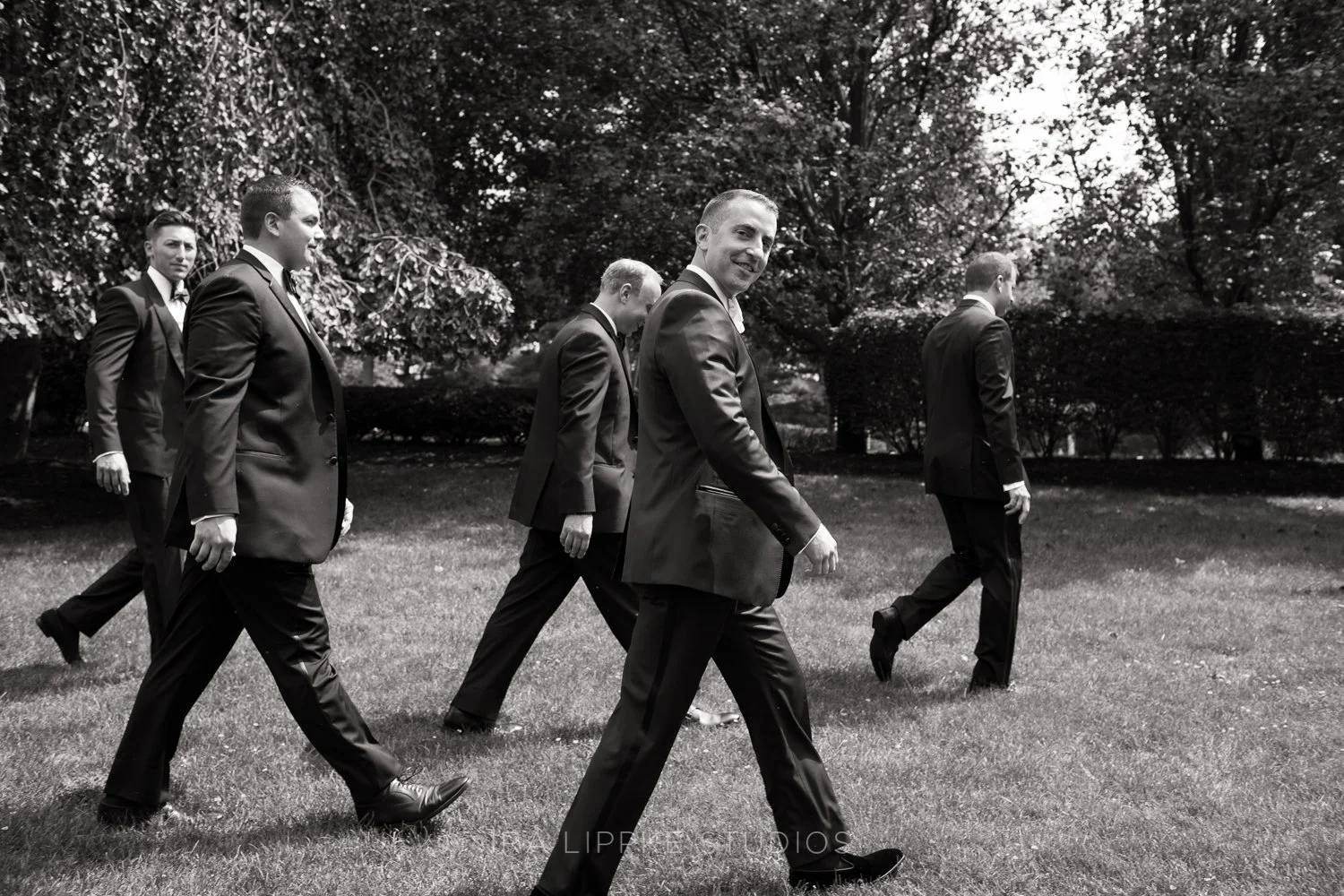 The groom shares a lighthearted moment with his groomsmen while strolling the grounds before the ceremony.