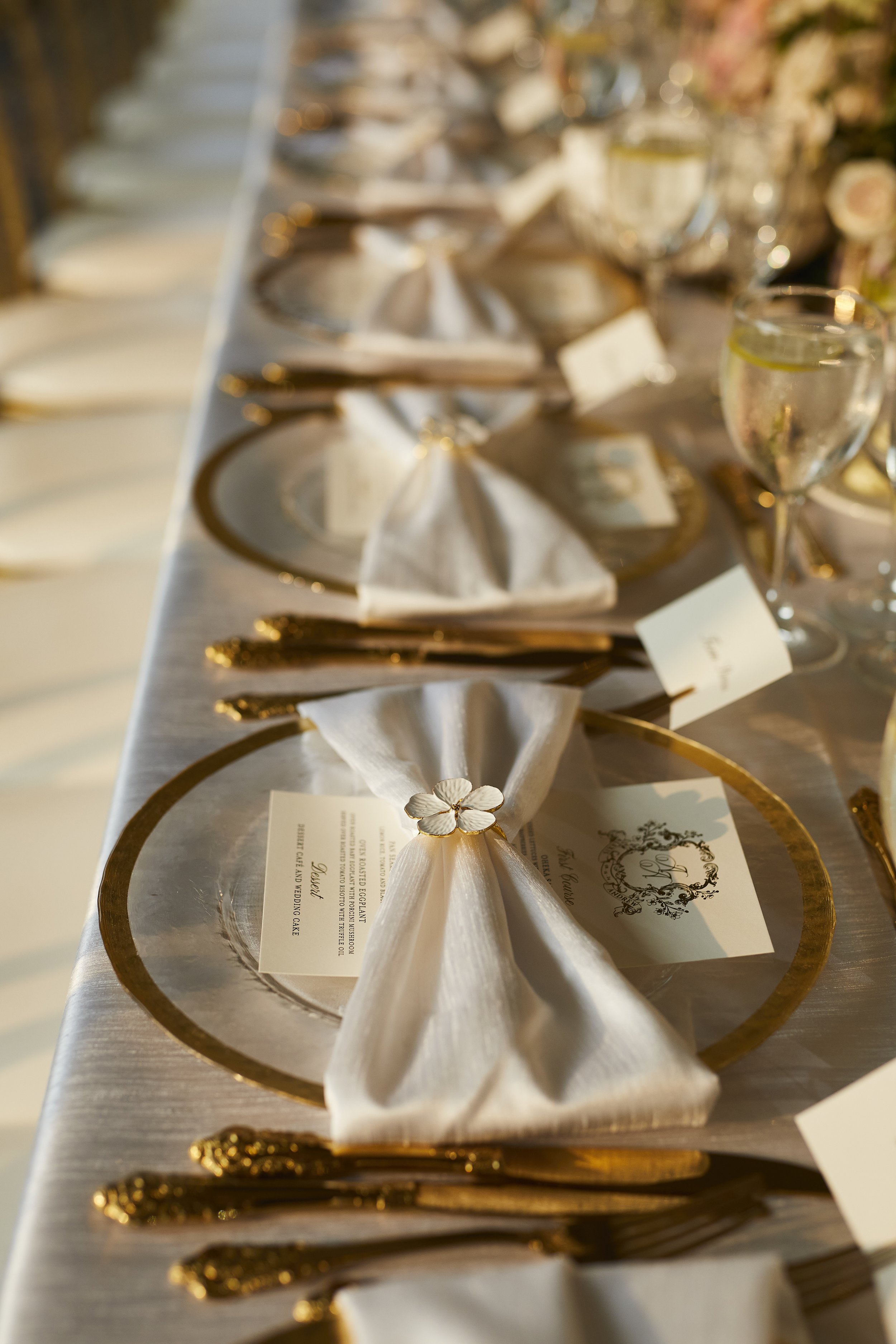 Elegant wedding table setting with gold flatware, charger plates, and custom place cards