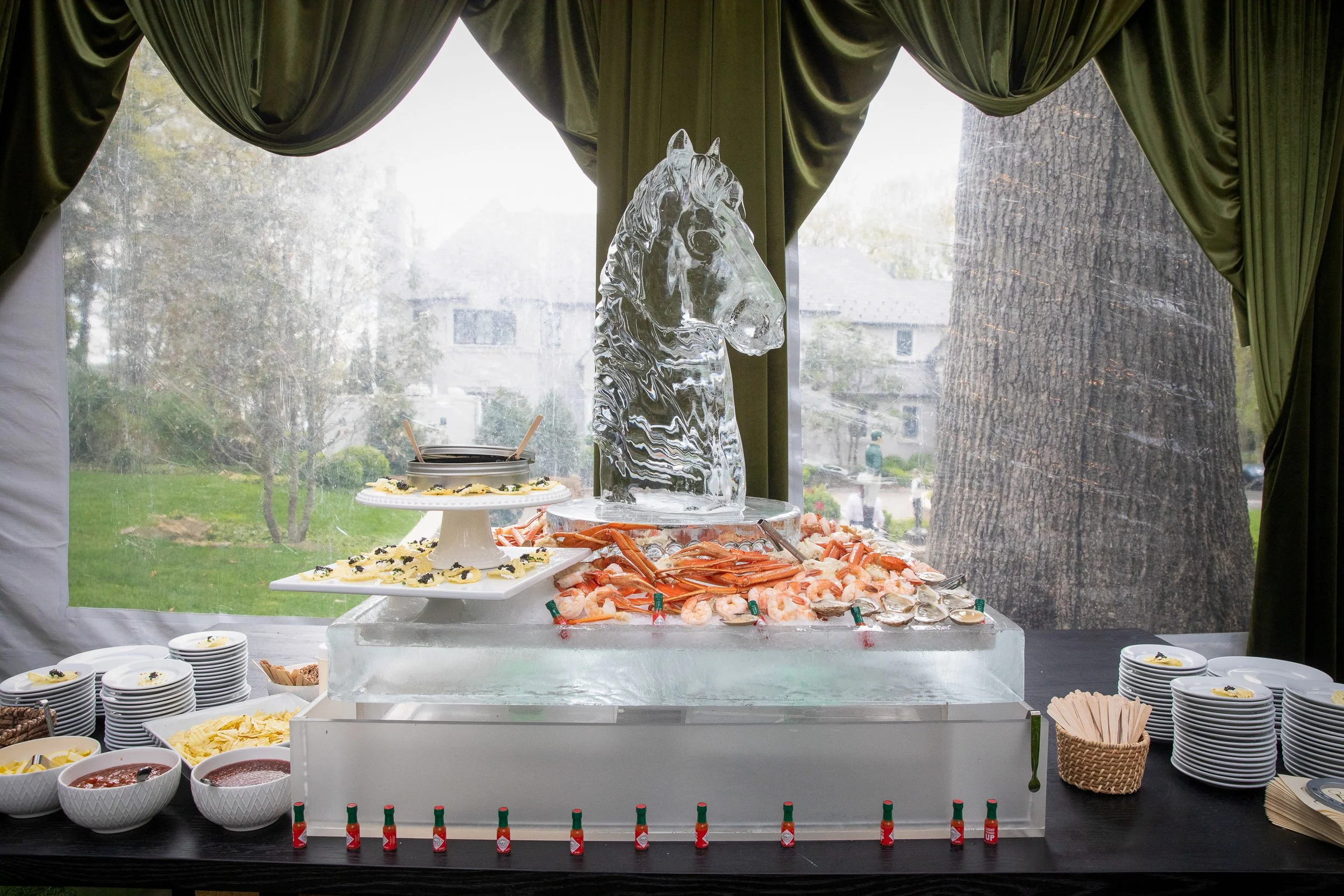 A sculpted raw bar centerpiece featuring an ice horse installation created as a dramatic focal point for cocktail hour.