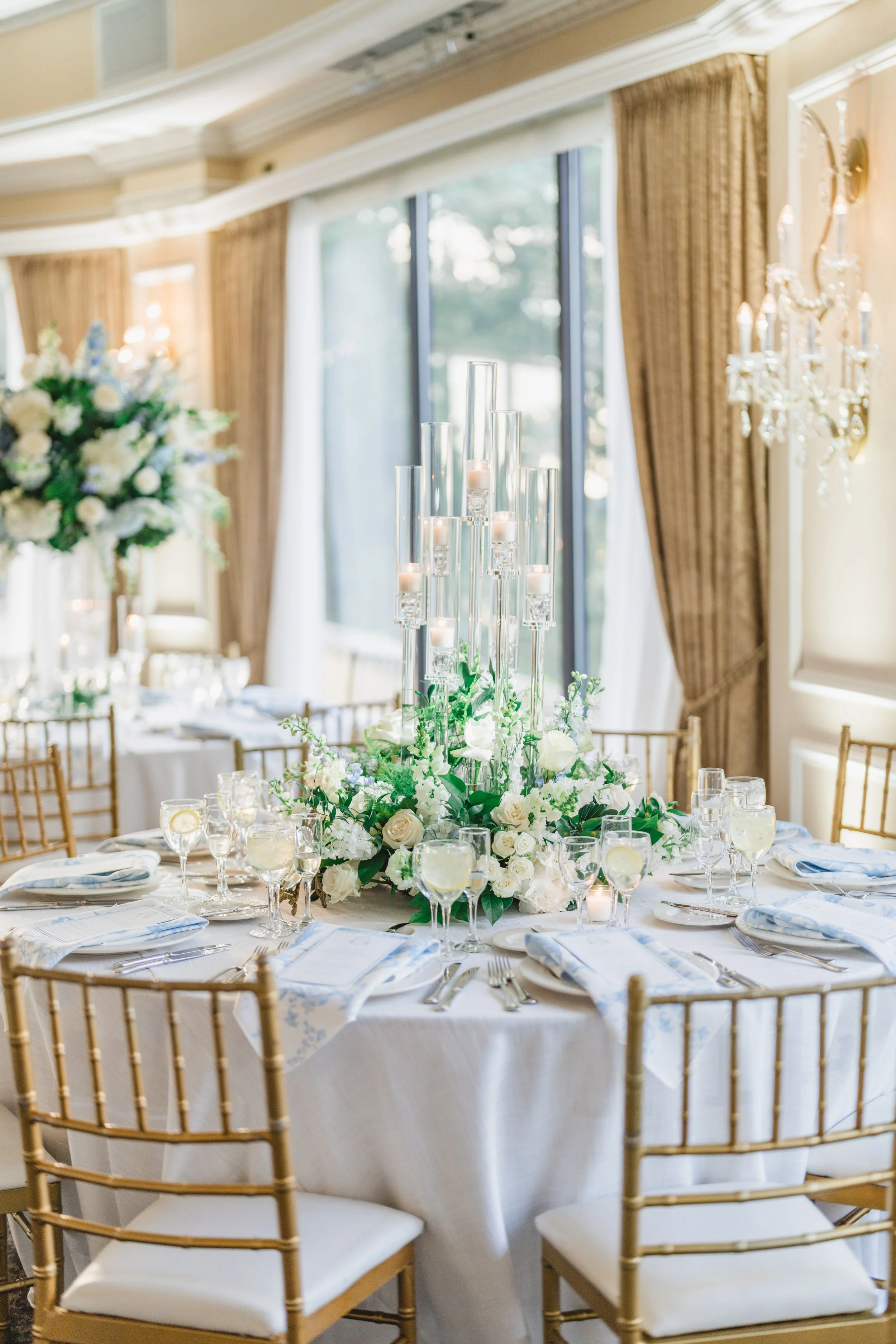 Round reception table with white and blue floral centerpiece and candlelight at Oheka Castle