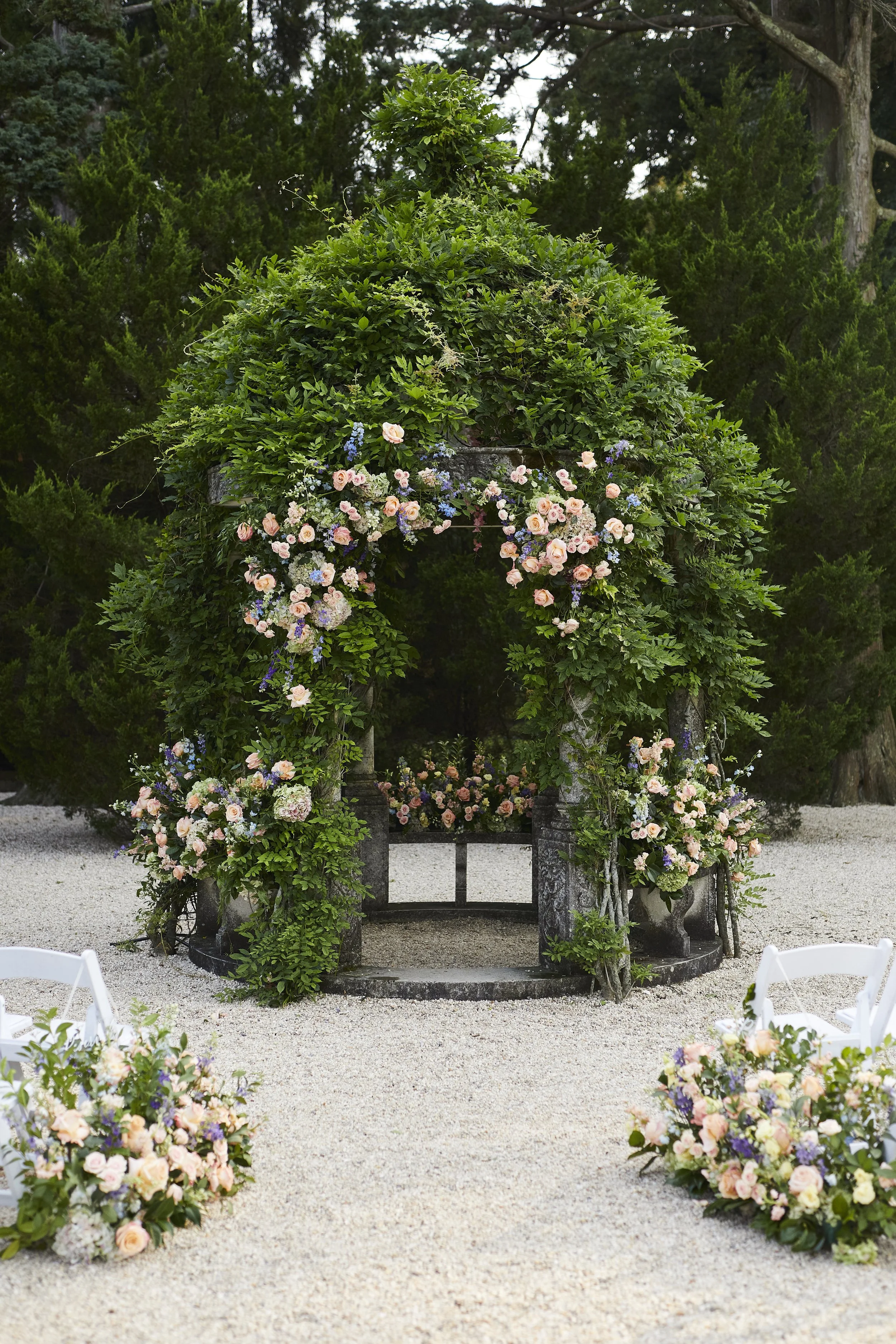 Floral-covered ceremony structure with garden-inspired greenery and pastel blooms at Oheka Castle