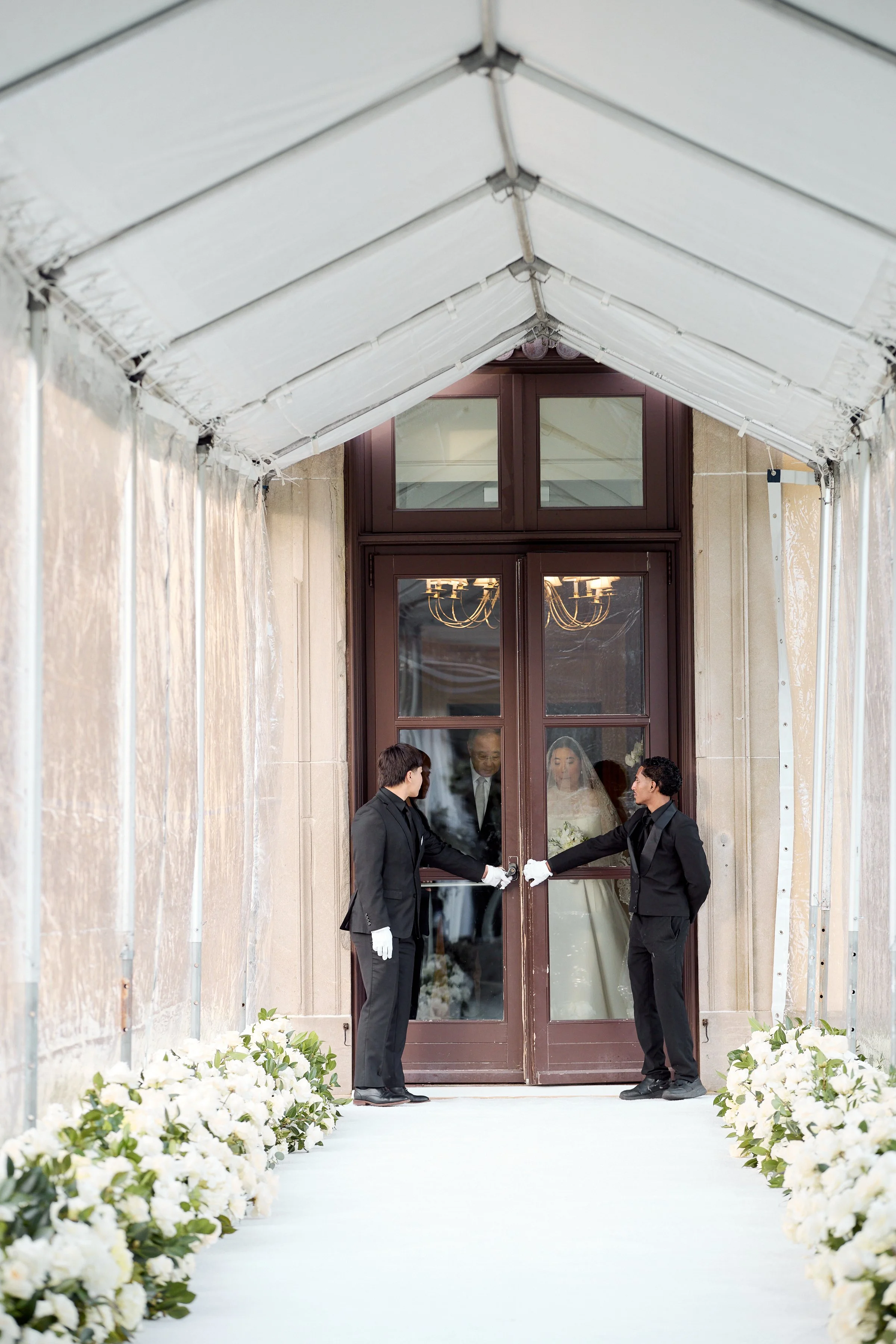 A dramatic reveal as guests anticipate the brides entrance into a light-filled, all-white ceremony space overlooking the Water Gardens.

