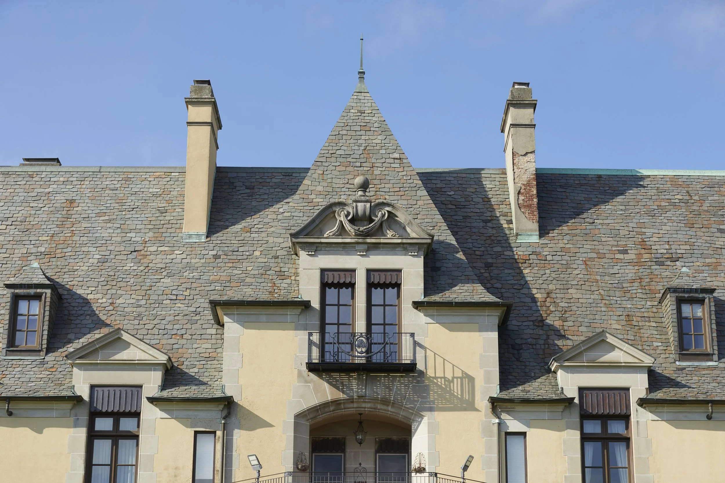 The iconic château-inspired architecture of Oheka Castle framed against a clear summer sky on the wedding day.
