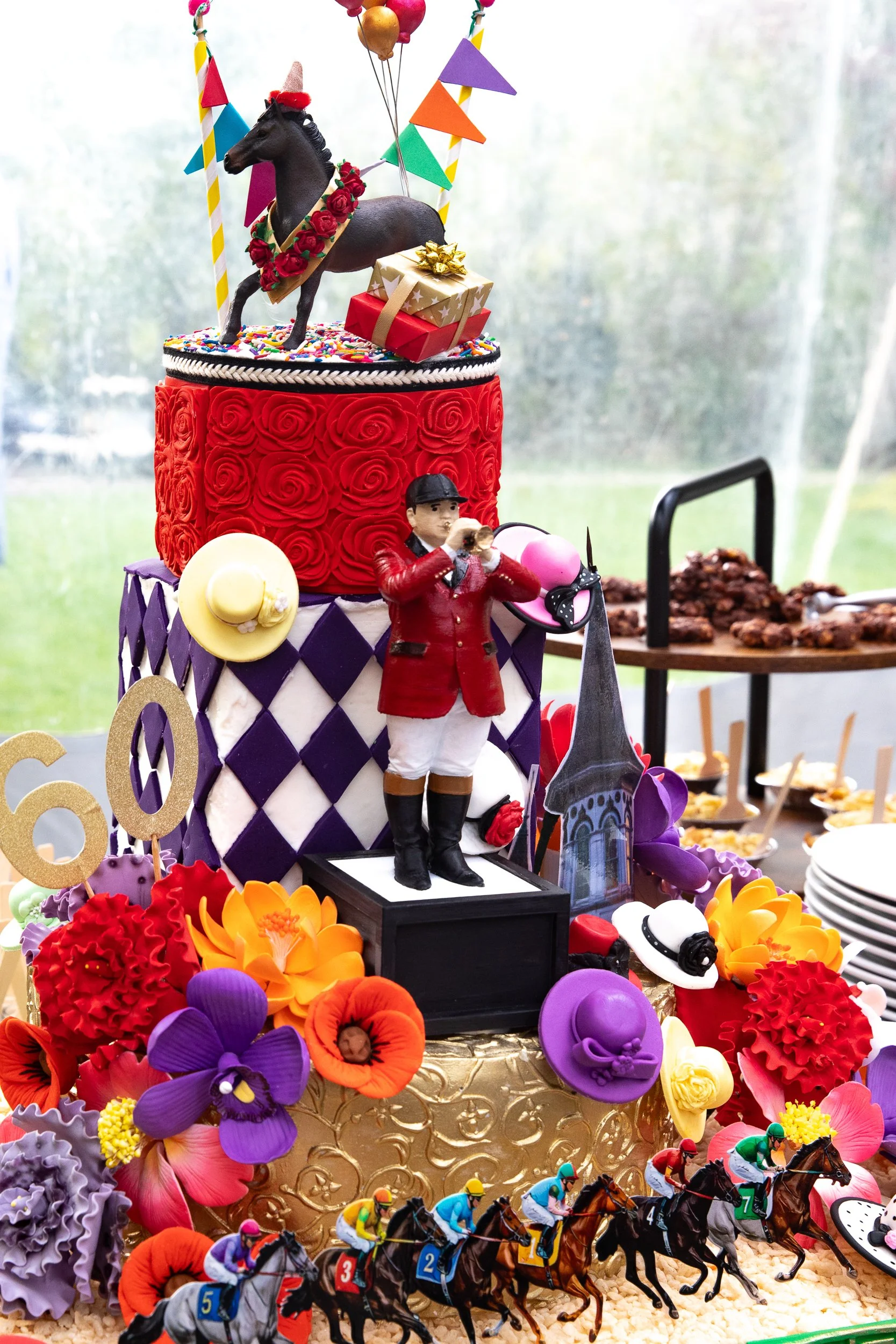 A whimsical Derby-inspired confection display layered with florals, racing silks, and vibrant equestrian details.