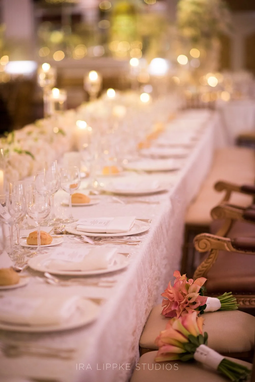 Long banquet tables are dressed with fine linens, floral accents, and candlelight, creating a warm and romantic dining experience.