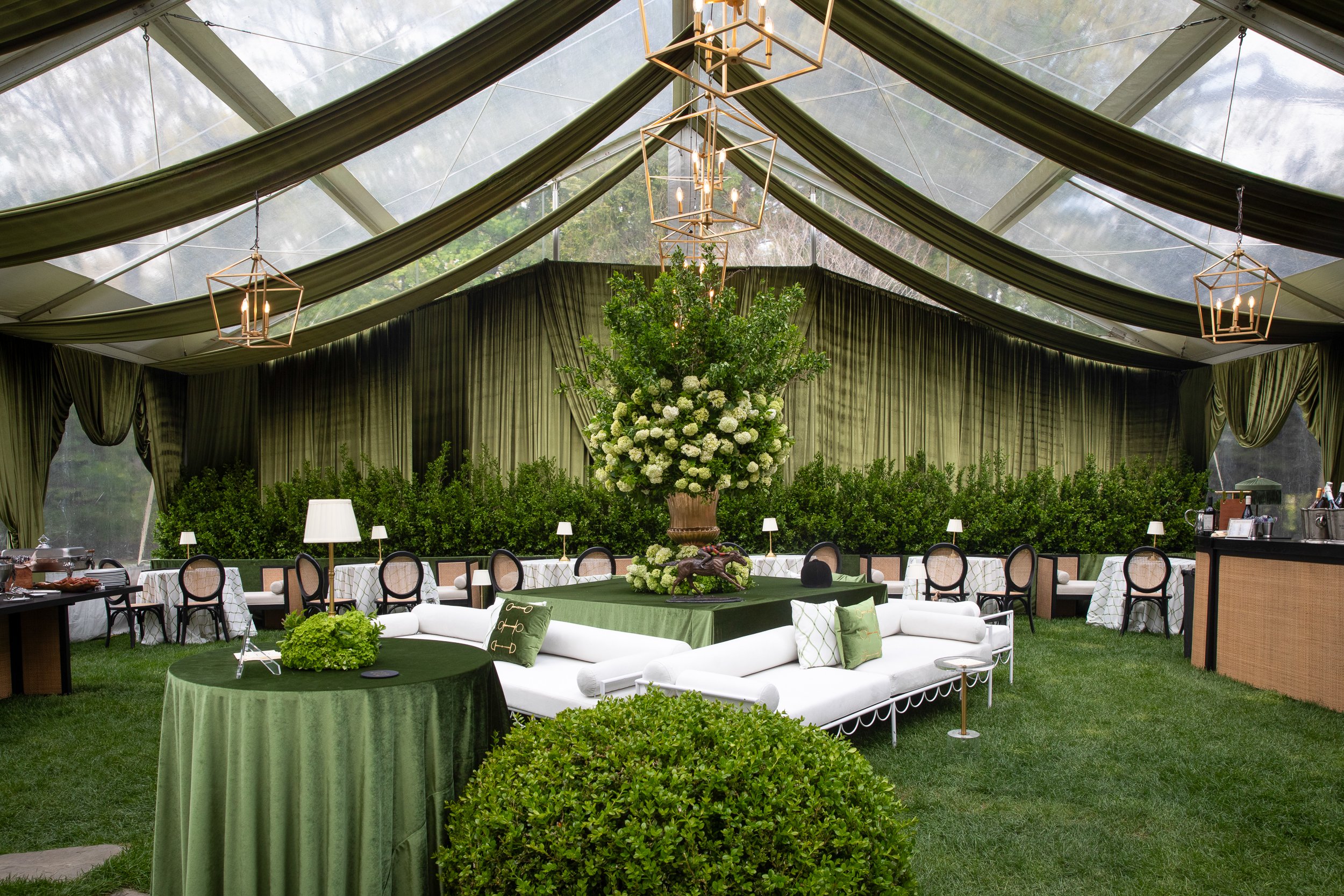 A custom tented Kentucky Derby environment layered with hunter green draping, tailored lounge seating, and lush equestrian-inspired florals at a private Lloyd Harbor estate.