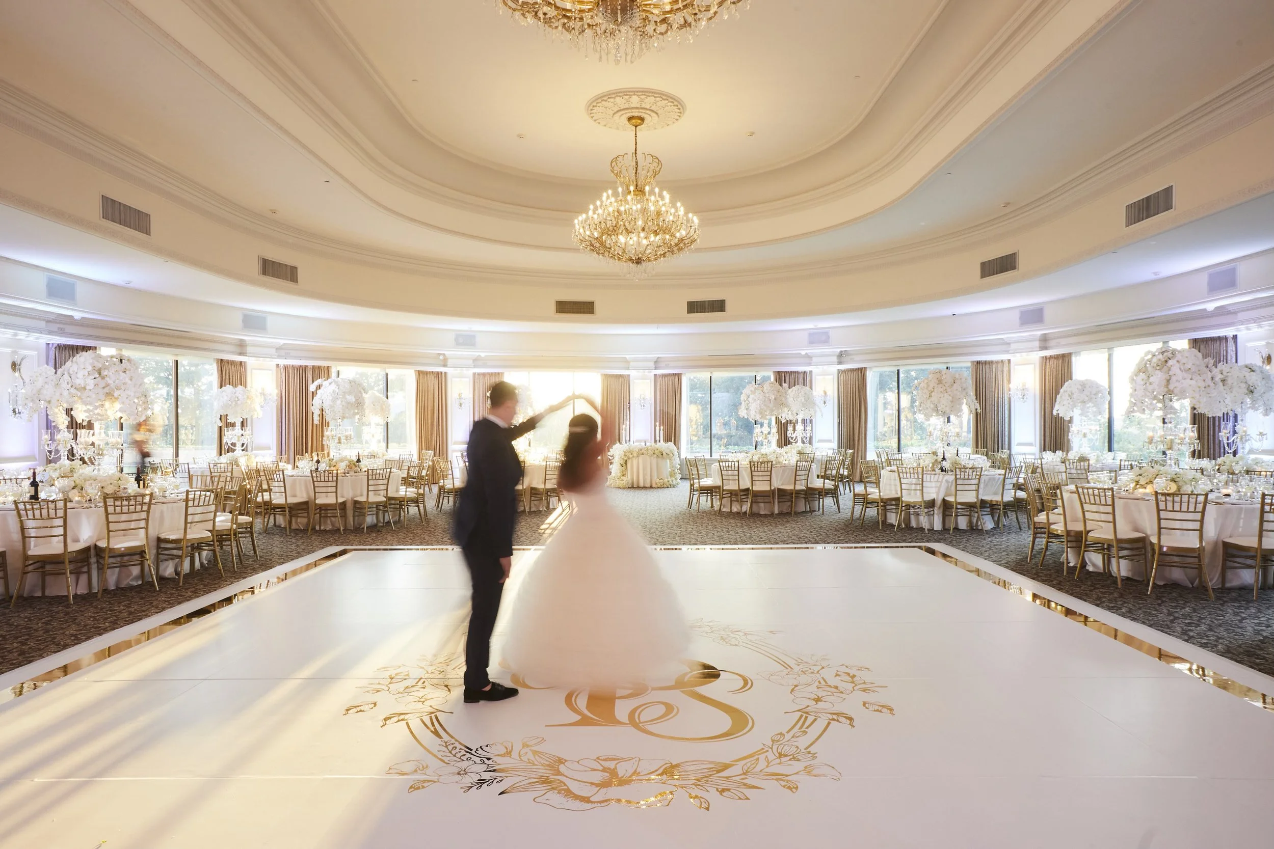 Bride and Groom practicing their first dance on a monogrammed dance floor before guests enter. 