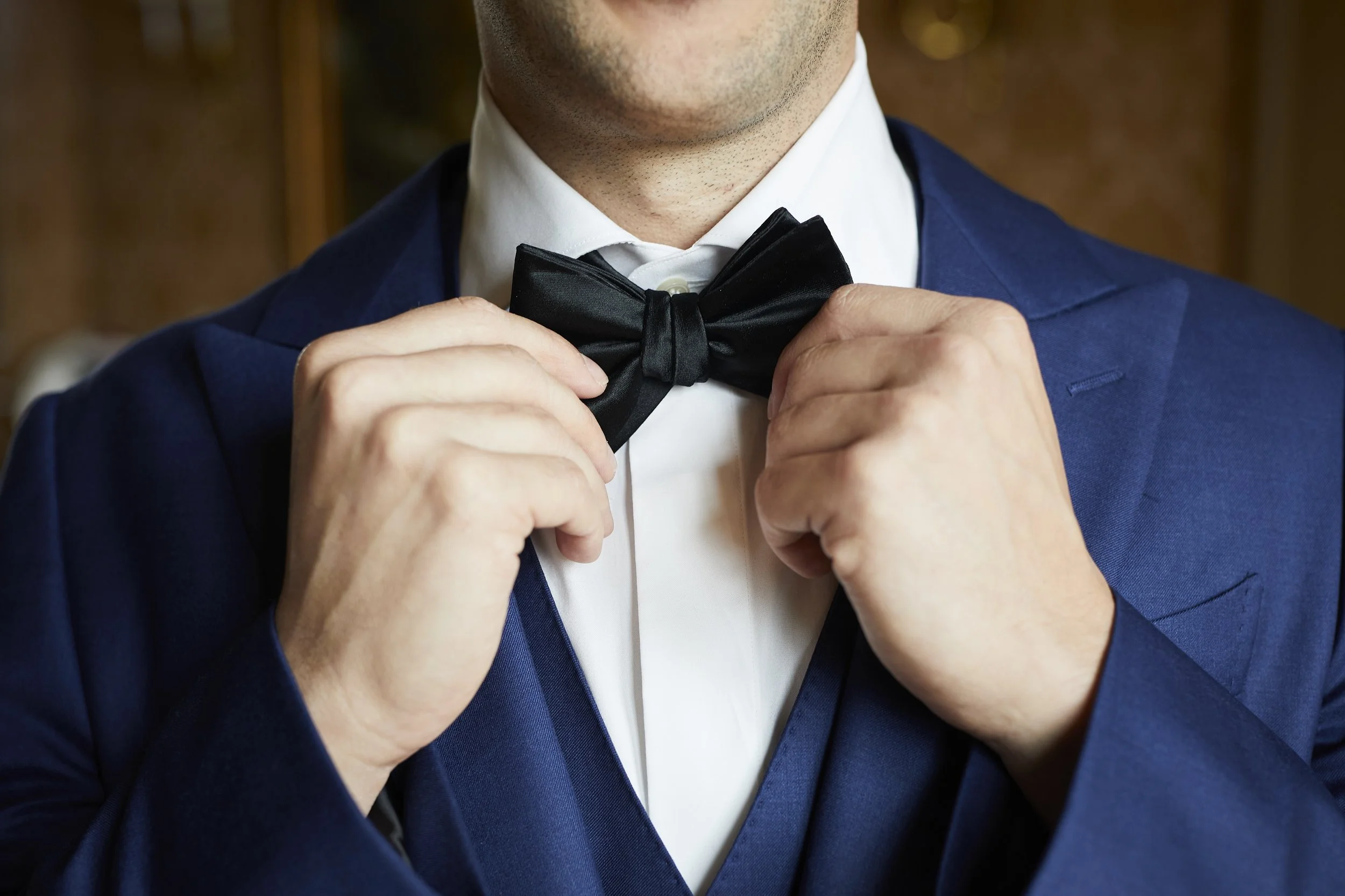 Groom adjusting his bowtie while getting ready for his wedding day
