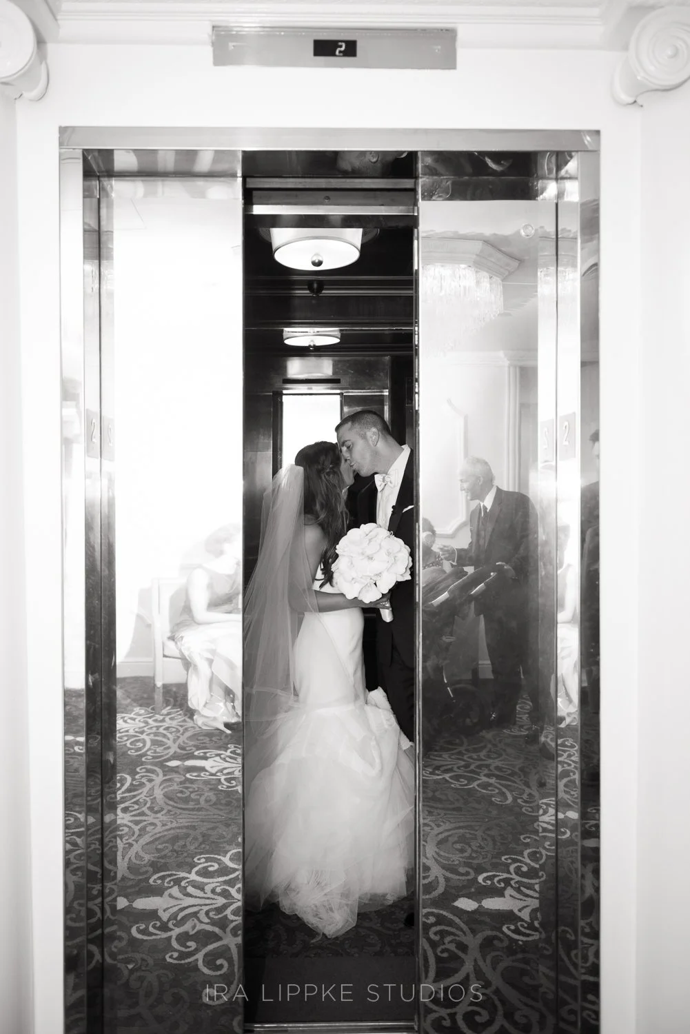 The bride stands in the elevator with her bouquet in hand, creating a cinematic image that beautifully bridges anticipation and celebration.
