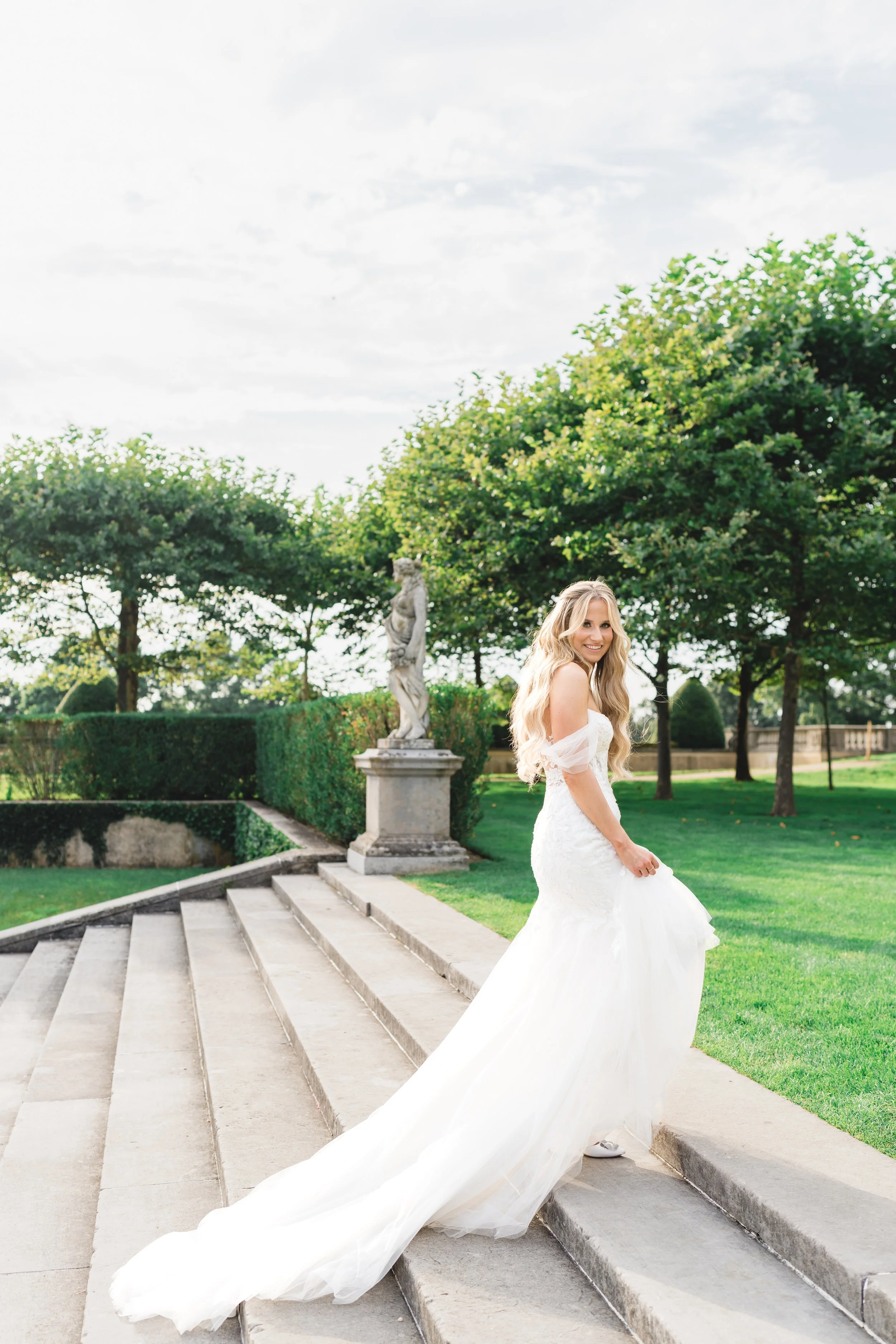 Bride walking down garden steps in flowing wedding gown at Oheka Castle estate