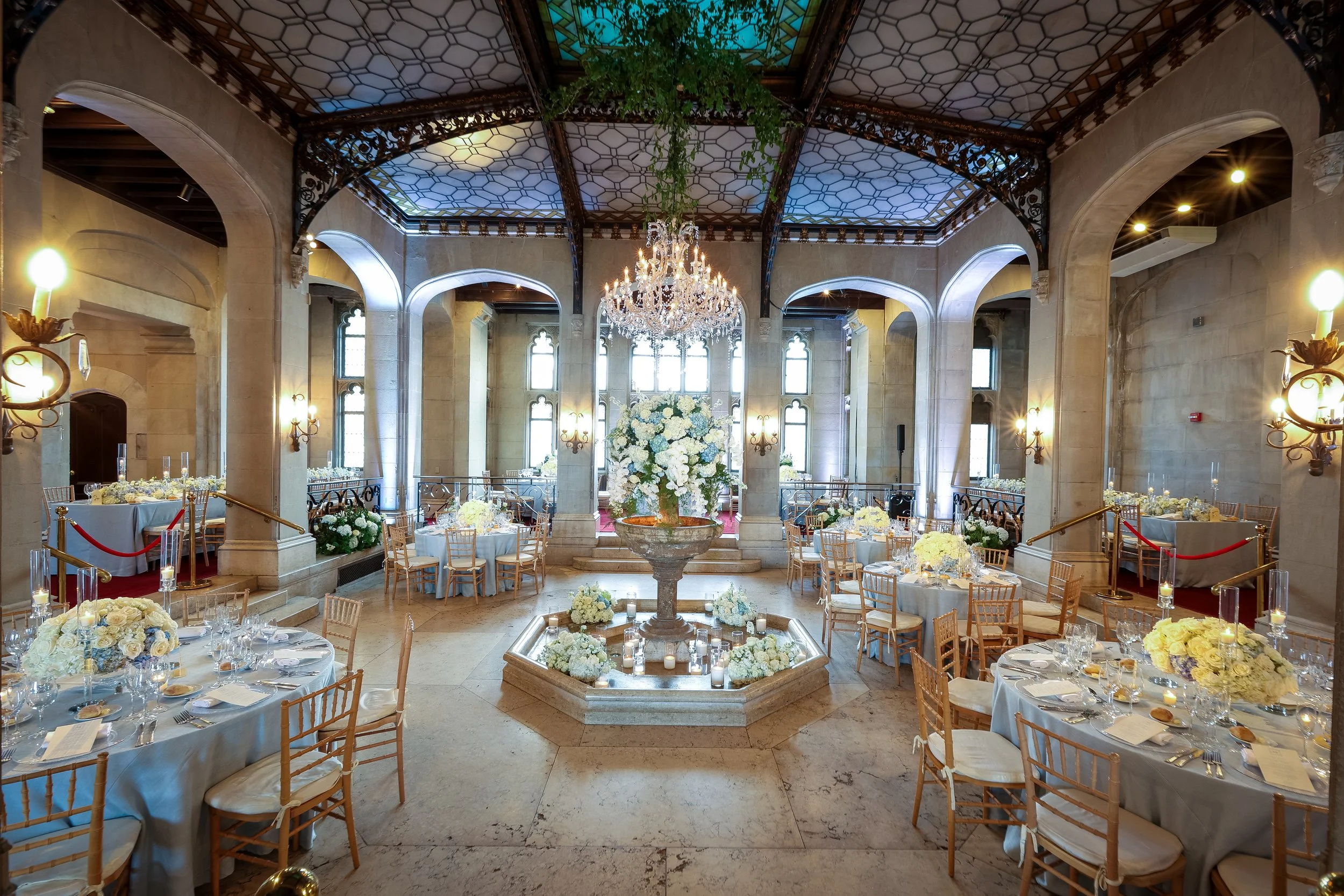 Hempstead House wedding reception with chandelier, central fountain, and elegant blue and ivory tablescape