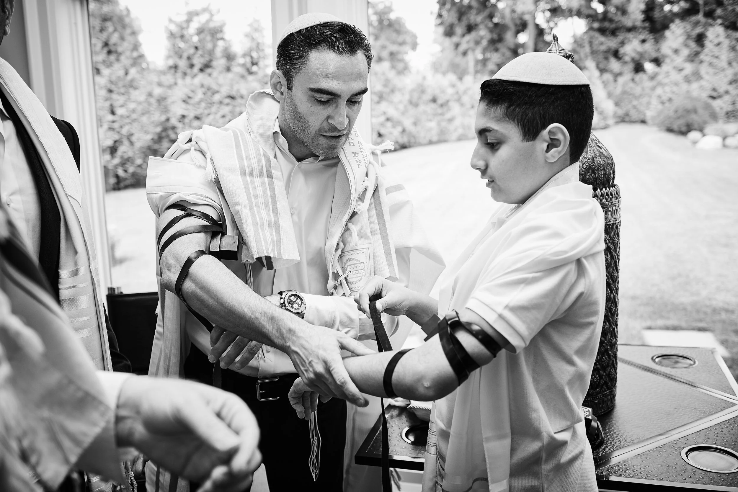 Tefillin wrapping ceremony during Skyler’s Bar Mitzvah at Cipriani Wall Street in New York City — a quiet, instructional moment as tradition is passed down with care, precision, and deep significance.