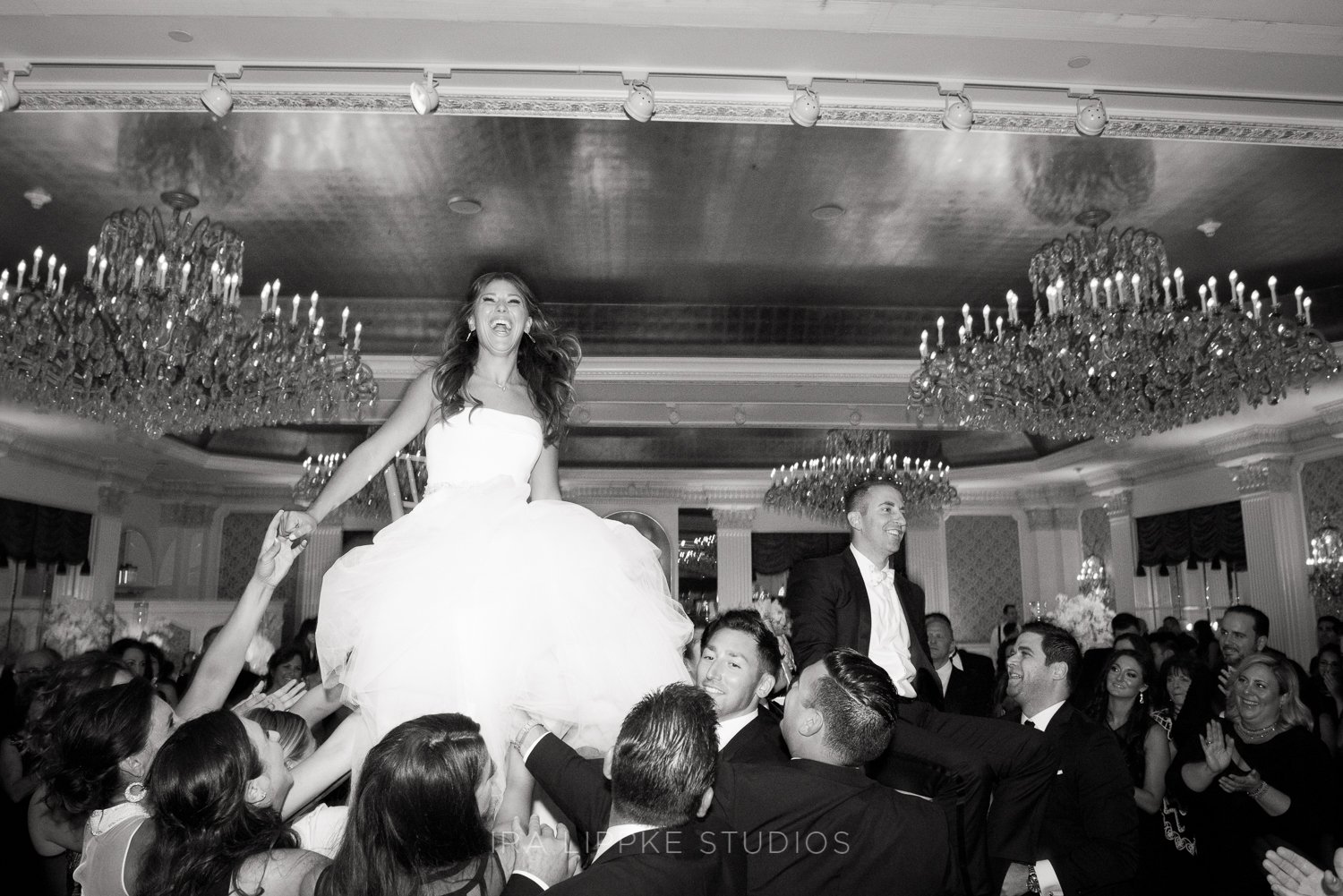The bride and groom are lifted high above the dance floor during the traditional hora, surrounded by cheering family and friends in one of the evening’s most energetic and memorable moments.