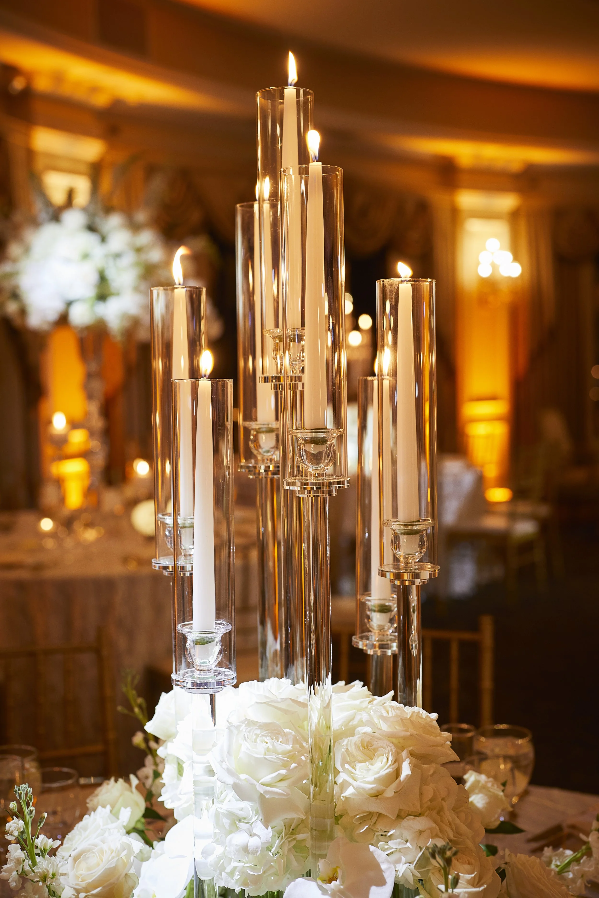 Glowing candelabra centerpiece with white roses at the base.