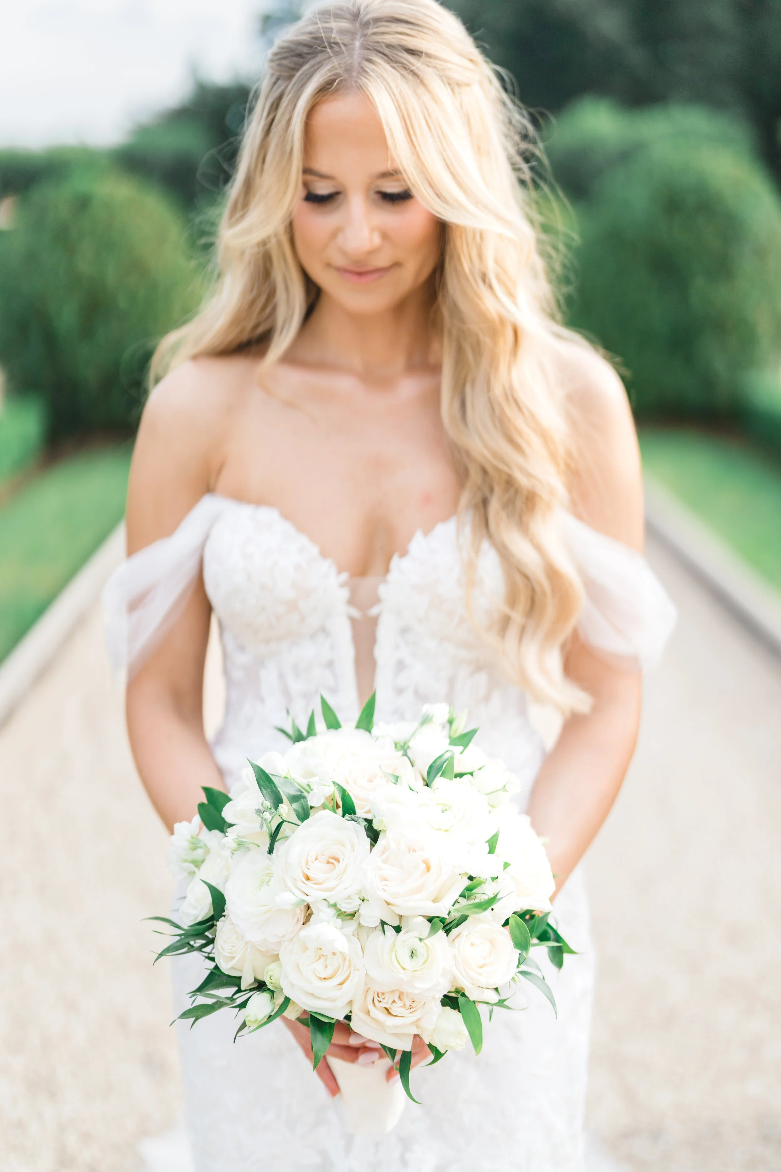 Bride holding white rose bouquet in soft natural light portrait at Oheka Castle