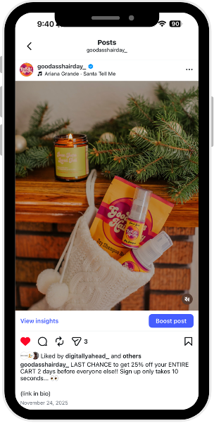 A Christmas-themed arrangement on a wooden surface, including a small jar candle, a packet of Foot Defender spray, and a sock stocking with white pom-poms, with pine branches in the background.