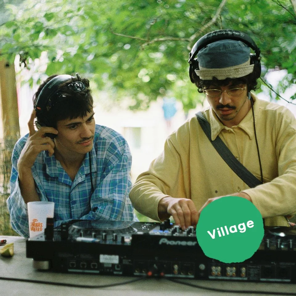 Deux hommes écoutent de la musique en utilisant des casques, devant un équipement de DJ, en plein air dans un environnement boisé
