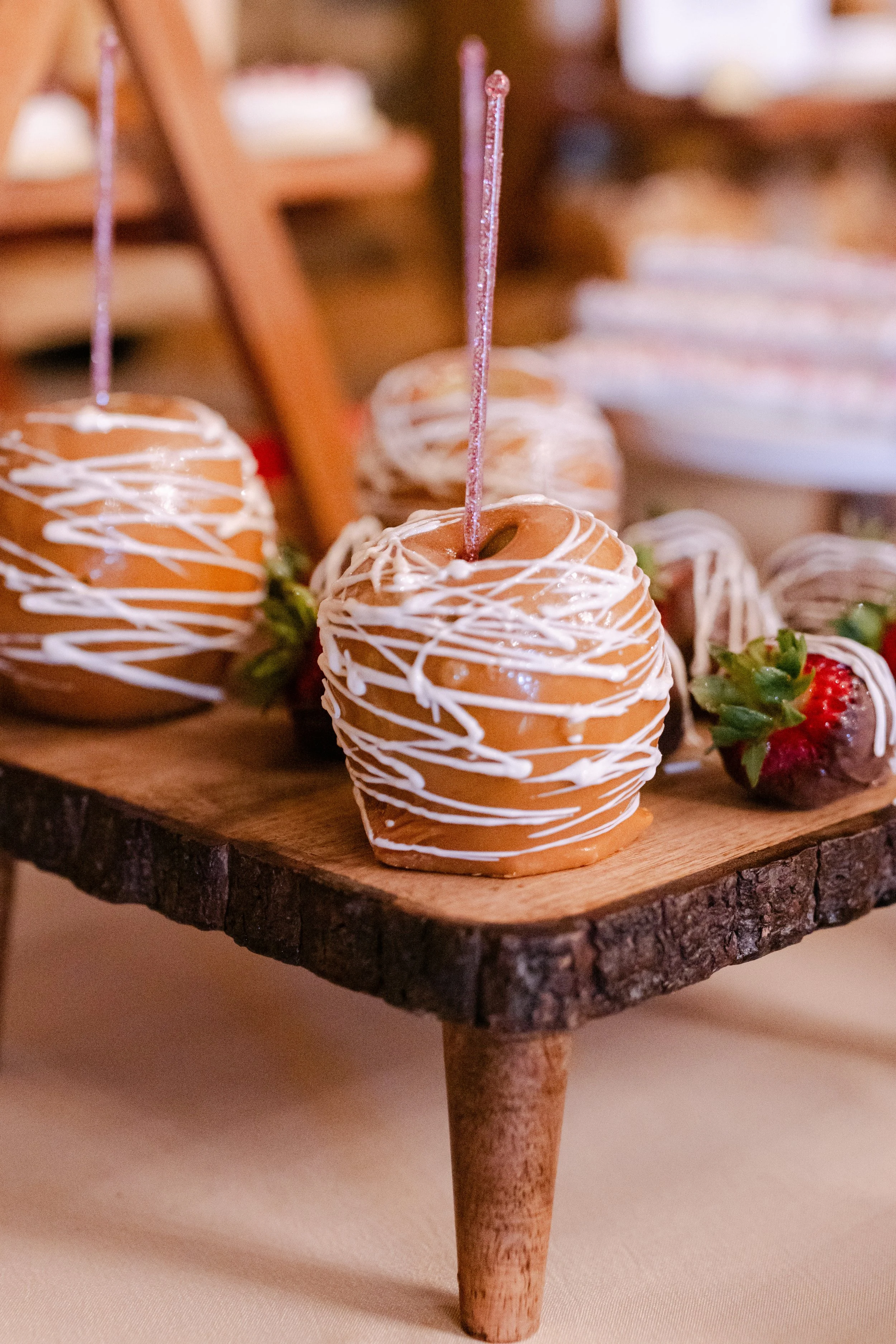 Chocolate-covered strawberries decorated with white drizzle on a rustic wooden serving tray.