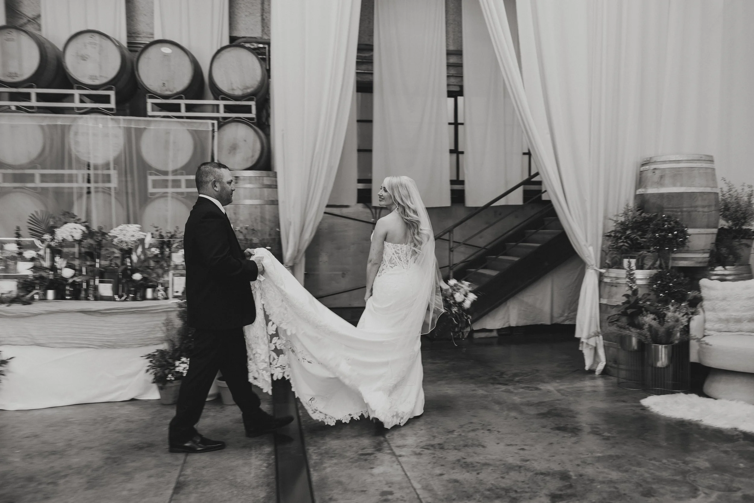 A bride and groom are dancing at their wedding reception, with the groom holding the bride's dress and the bride smiling.