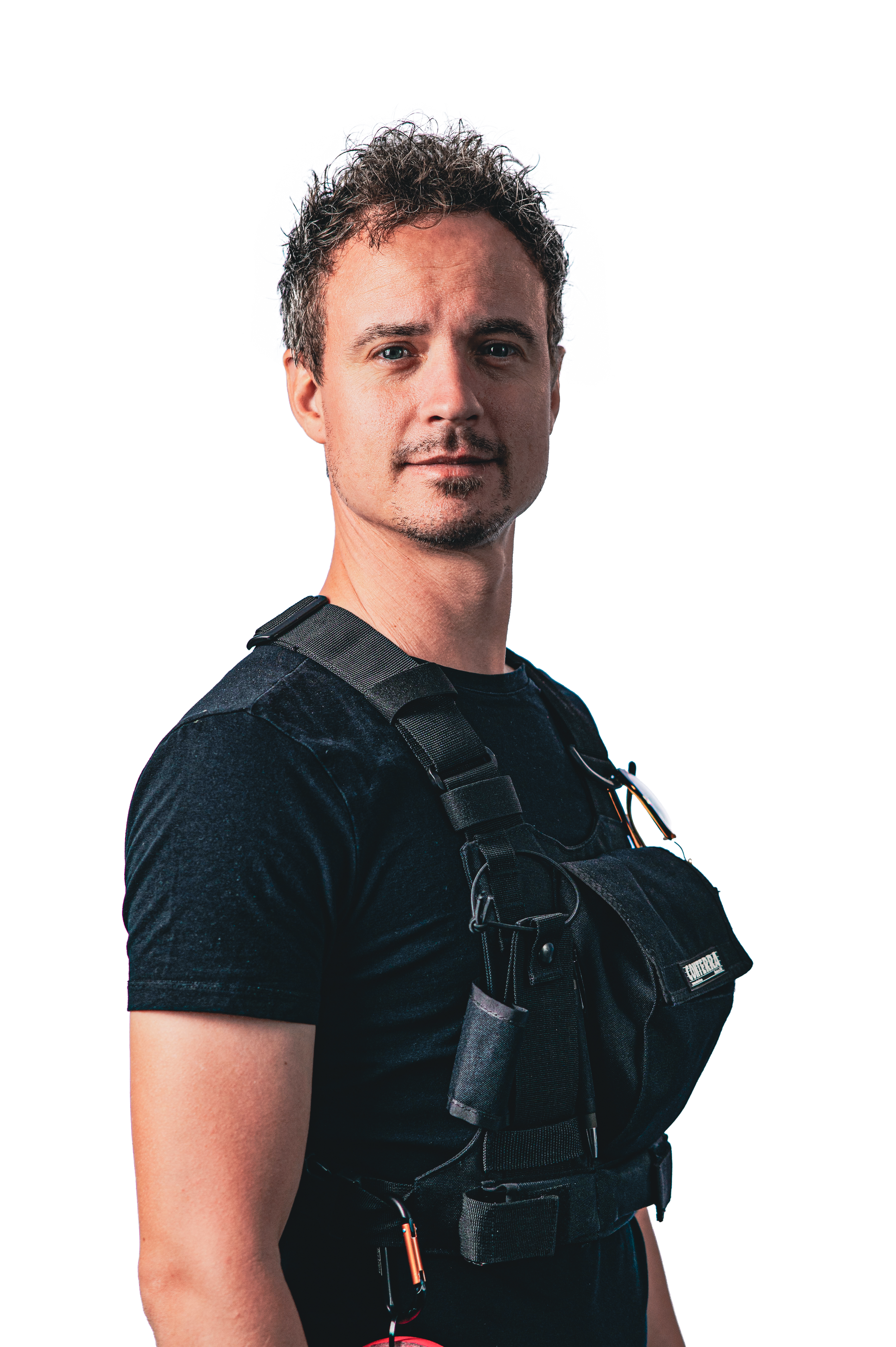 Man in zwart T-shirt met uitrusting en valhelm, kijkend naar de camera.