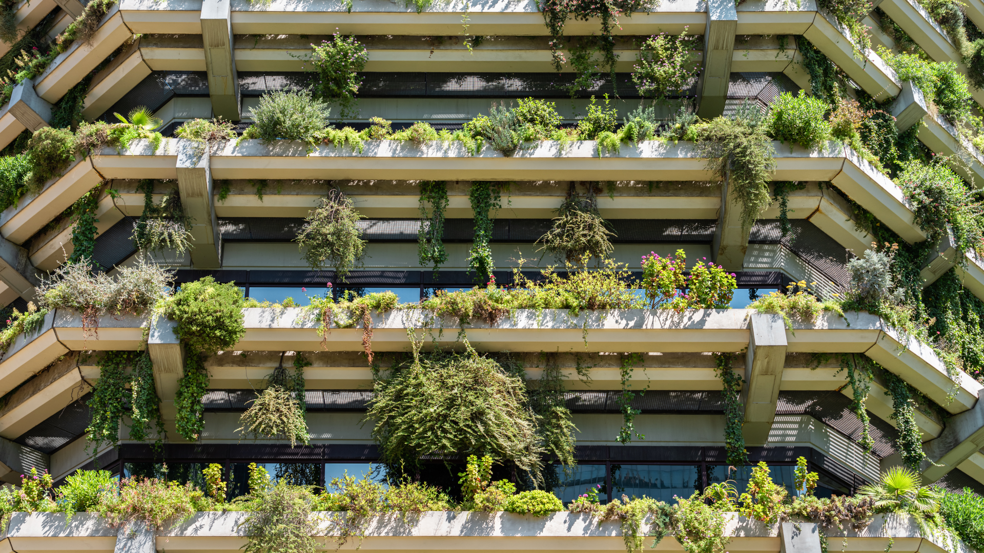 Edificio con jardines en cada balcón con plantas y árboles variados.