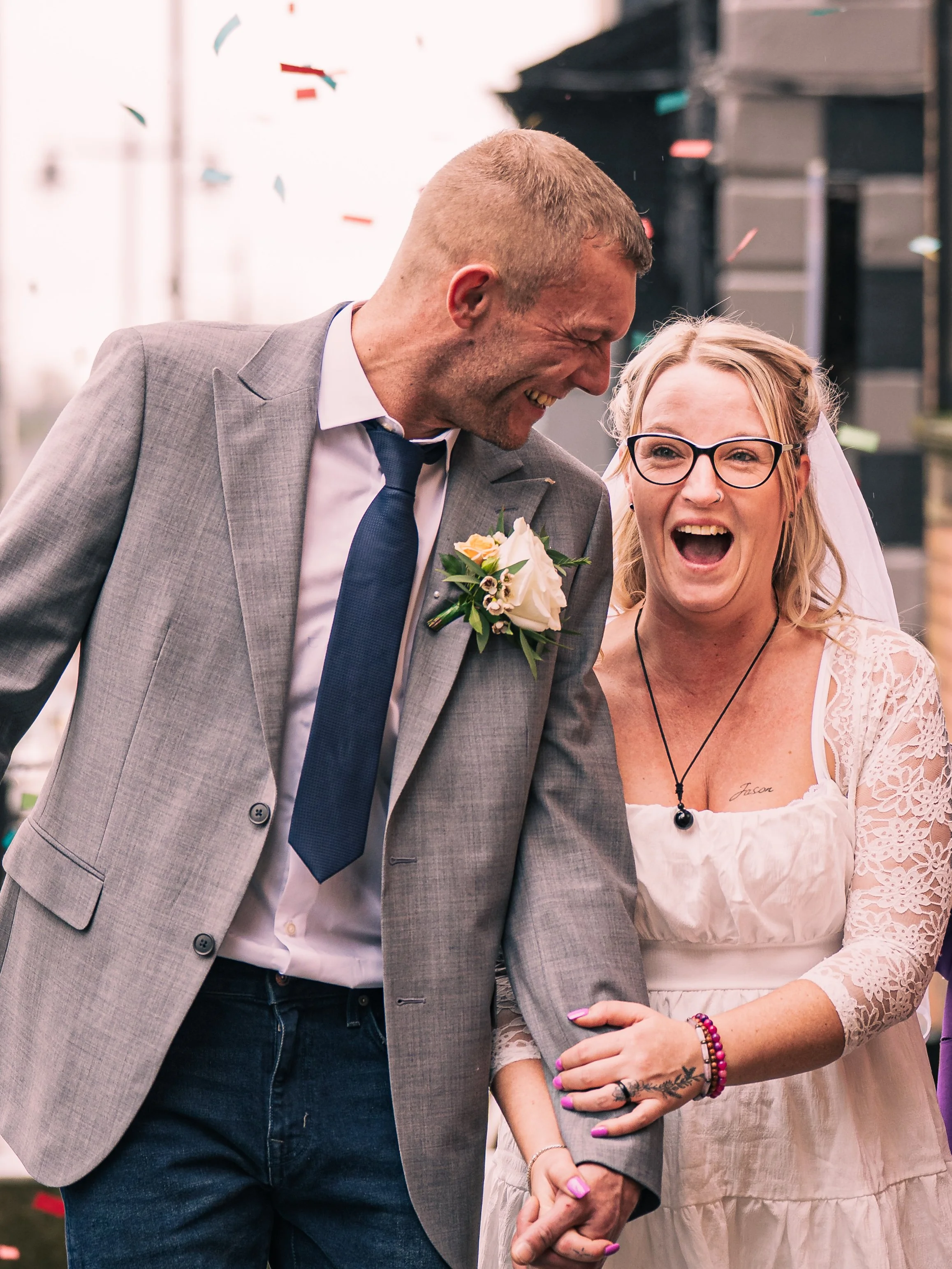 A happy bride and groom laughing and holding hands during their wedding celebration.