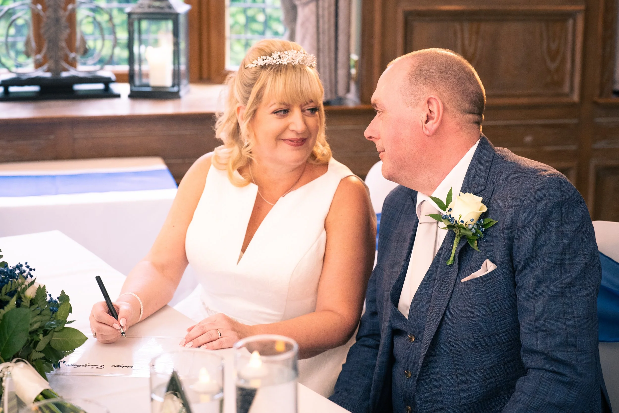 Woman in white dress looking at man in suit at wedding reception.