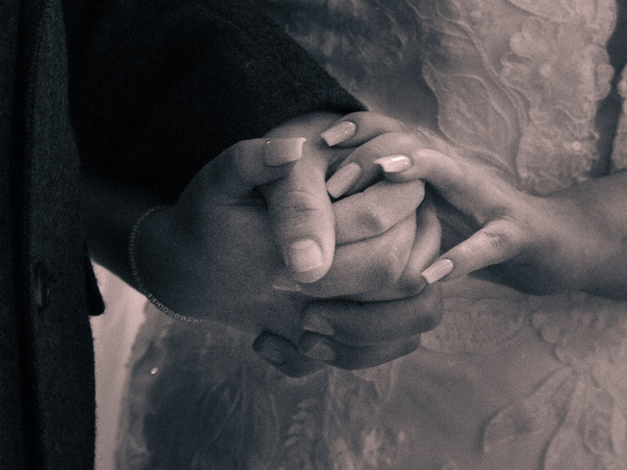 Two hands gently clasped together, resting on a patterned surface.