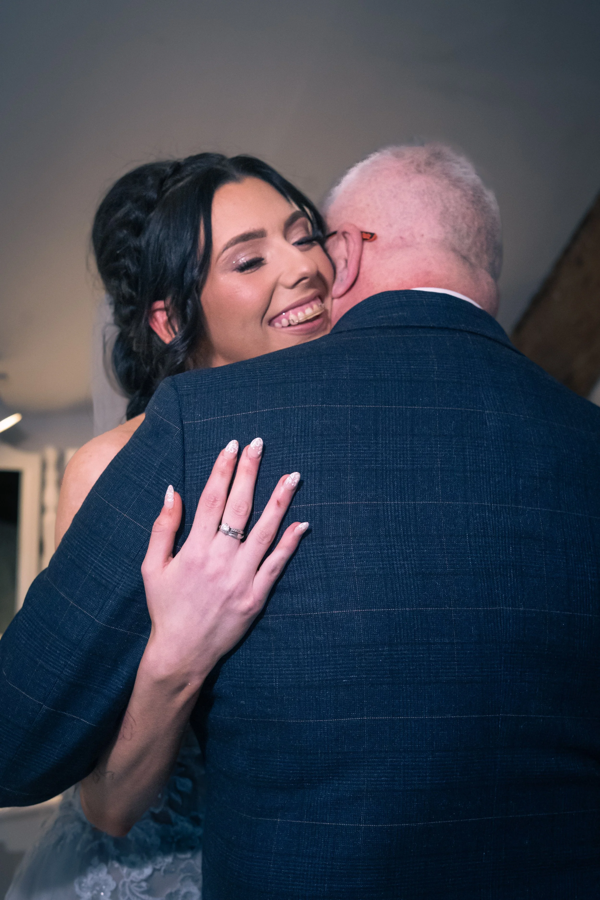 A bride happily embraces an older man, likely her father, during a wedding dance.