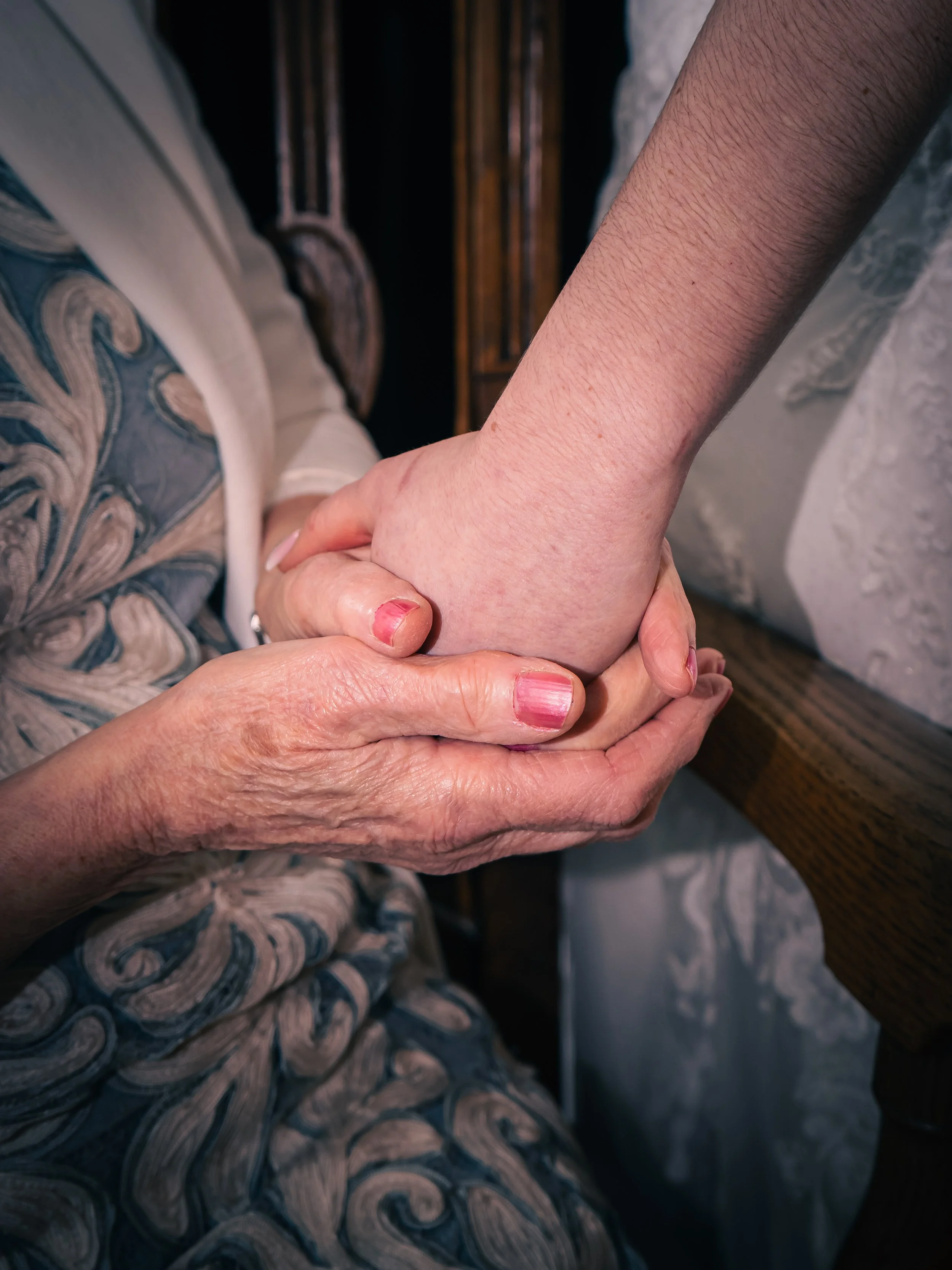 An elderly person holding a younger person's hand, showing a moment of support and care.