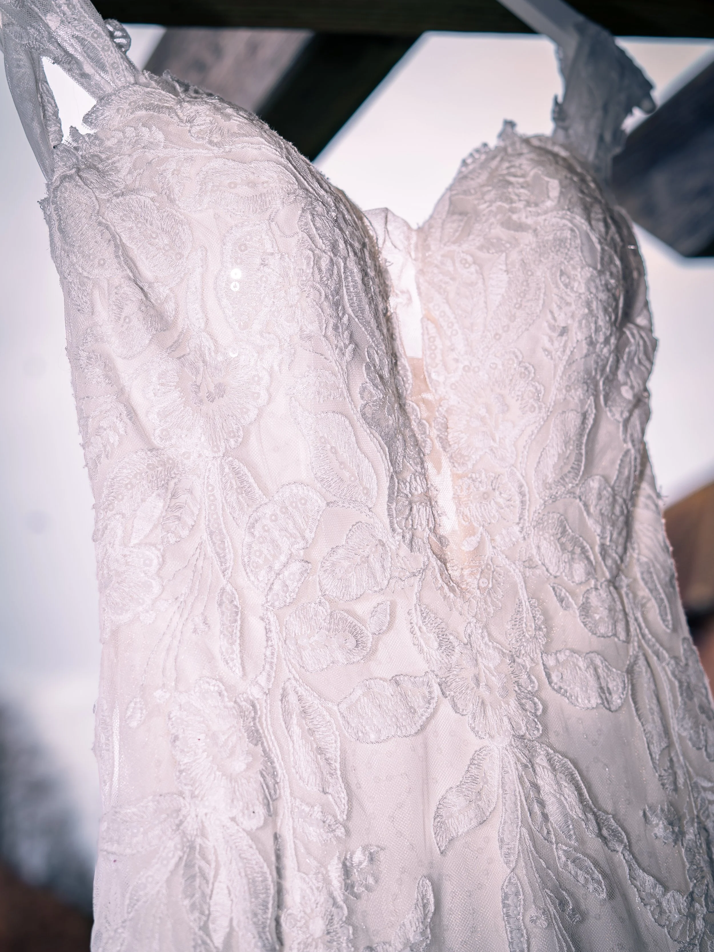 Close-up of a white lace wedding dress with floral embroidery and a sweetheart neckline.