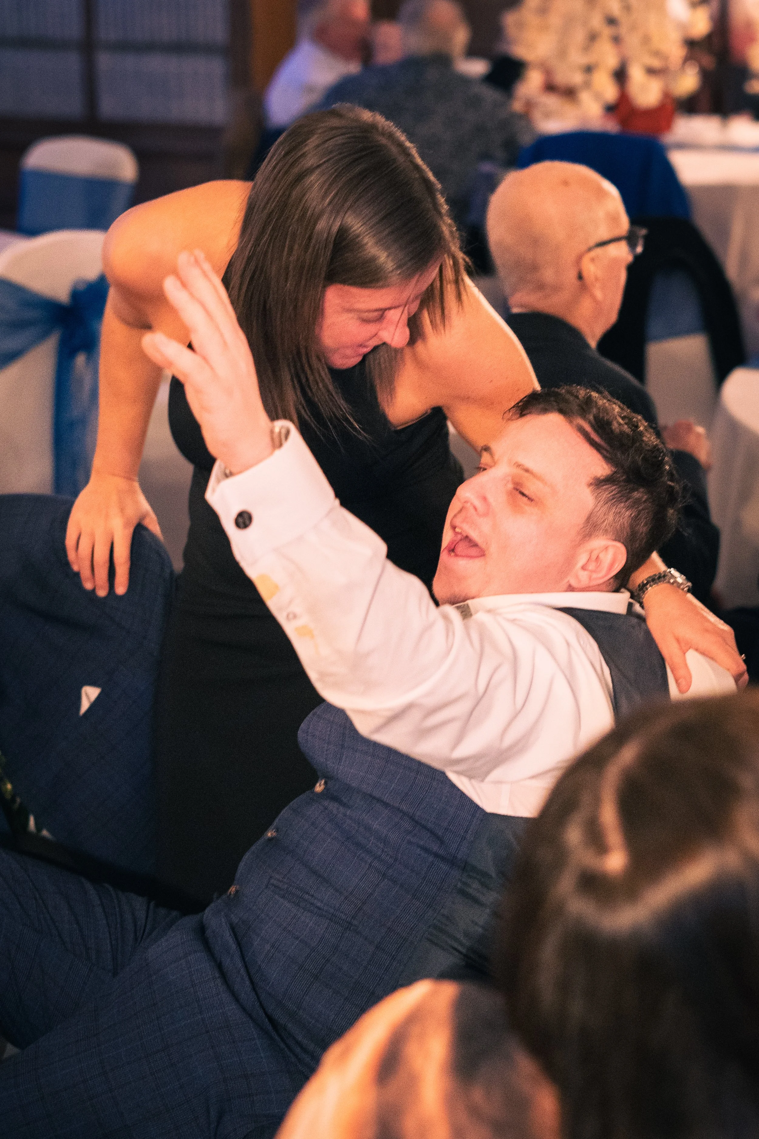 A woman and a man are dancing closely at a formal event, smiling and enjoying themselves.